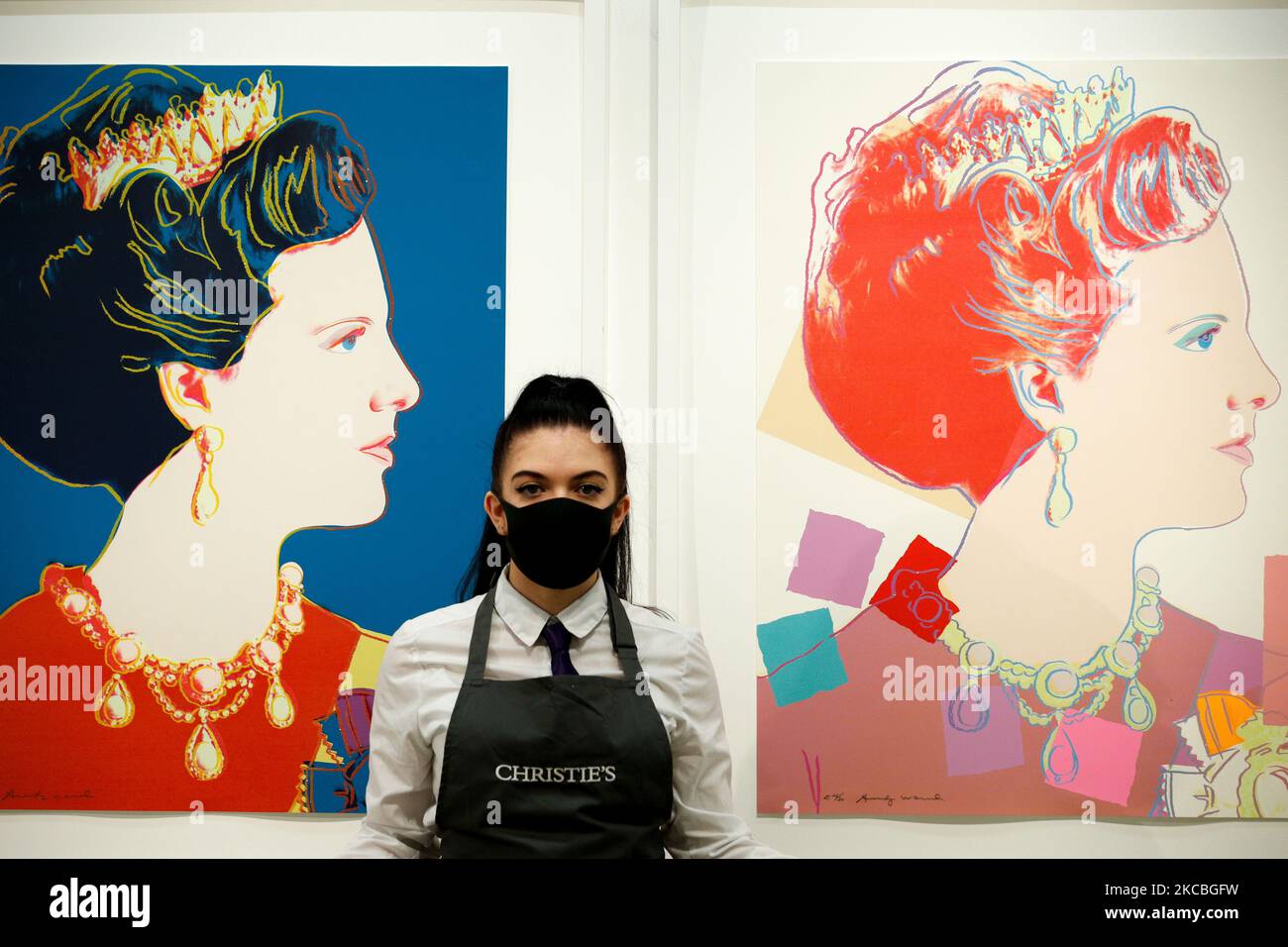 An art handler poses in front of two of a set of four artworks by American artist Andy Warhol 'Queen Margarethe II of Denmark, from: Reigning Queens (Royal Edition)', estimated at GBP60,000-80,000, during a press preview at Christie's auction house in London, England, on March 26, 2021. (Photo by David Cliff/NurPhoto) Stock Photo