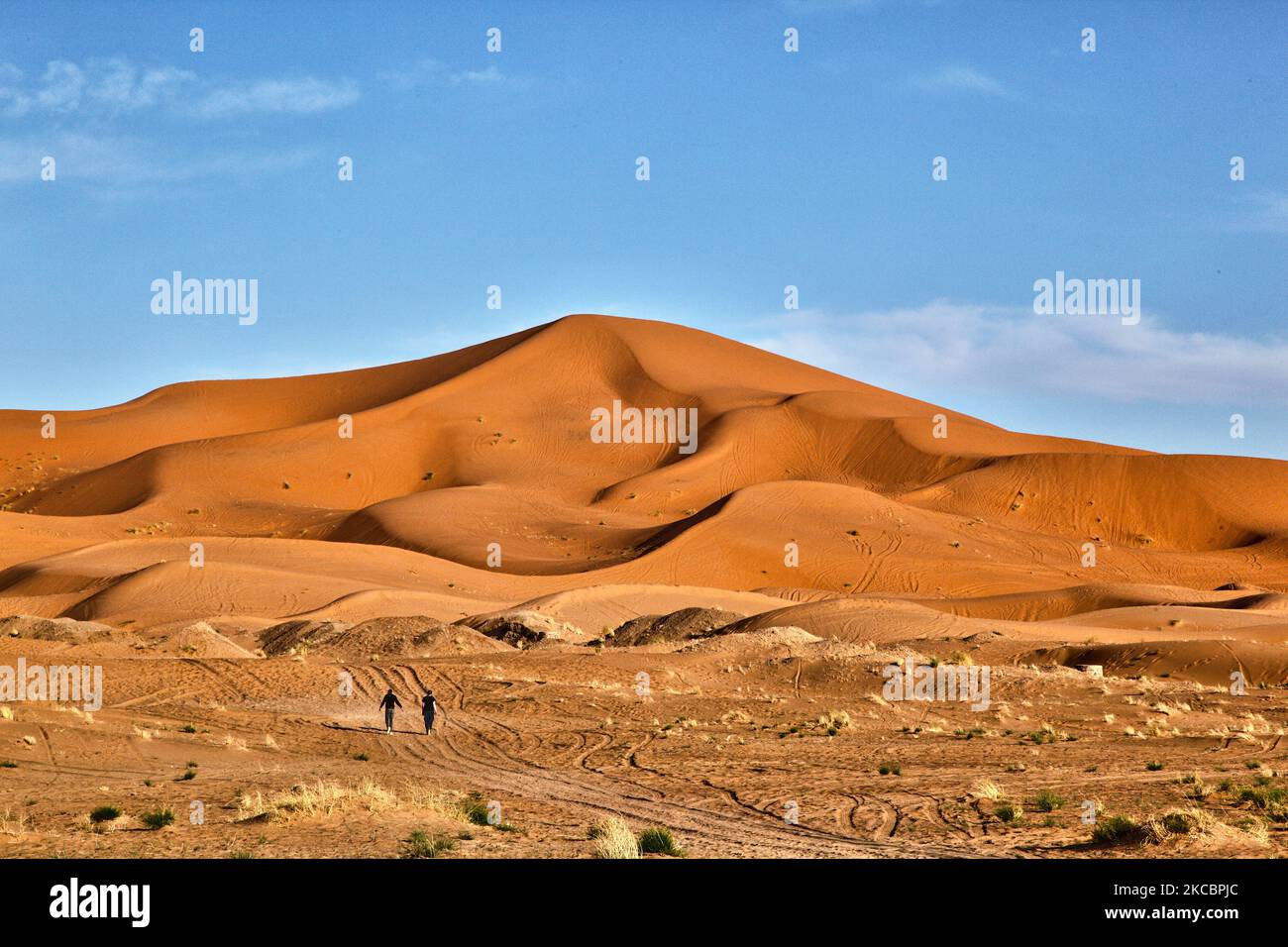 Tourists walk towards the sand dunes in the Erg Chebbi desert near the small village of Merzouga in Morocco, Africa. Merzouga is a village in the Sahara Desert in Morocco, on the edge of Erg Chebbi, a 50km long and 5km wide set of sand dunes that reach up to 350m. (Photo by Creative Touch Imaging Ltd./NurPhoto) Stock Photo