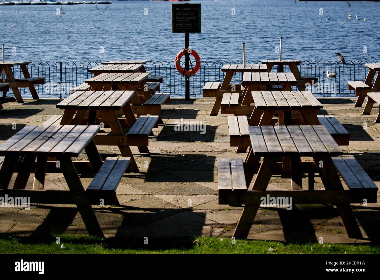 Empty tables sit out in the temporarily-closed outdoor seating area of a cafe beside the Serpentine lake in Hyde Park in London, England, on March 29, 2021. Lockdown restrictions were eased across England today, with the 'stay home' rule ended, groups of up to six allowed to meet outside, outdoor sports restarted and weddings with up to six people attending permitted to go ahead. Shops, hospitality and leisure businesses remain closed however, with the next relaxation of restrictions not due until April 12 at the earliest. Today's easing has meanwhile coincided with the first of a three-day 'm Stock Photo