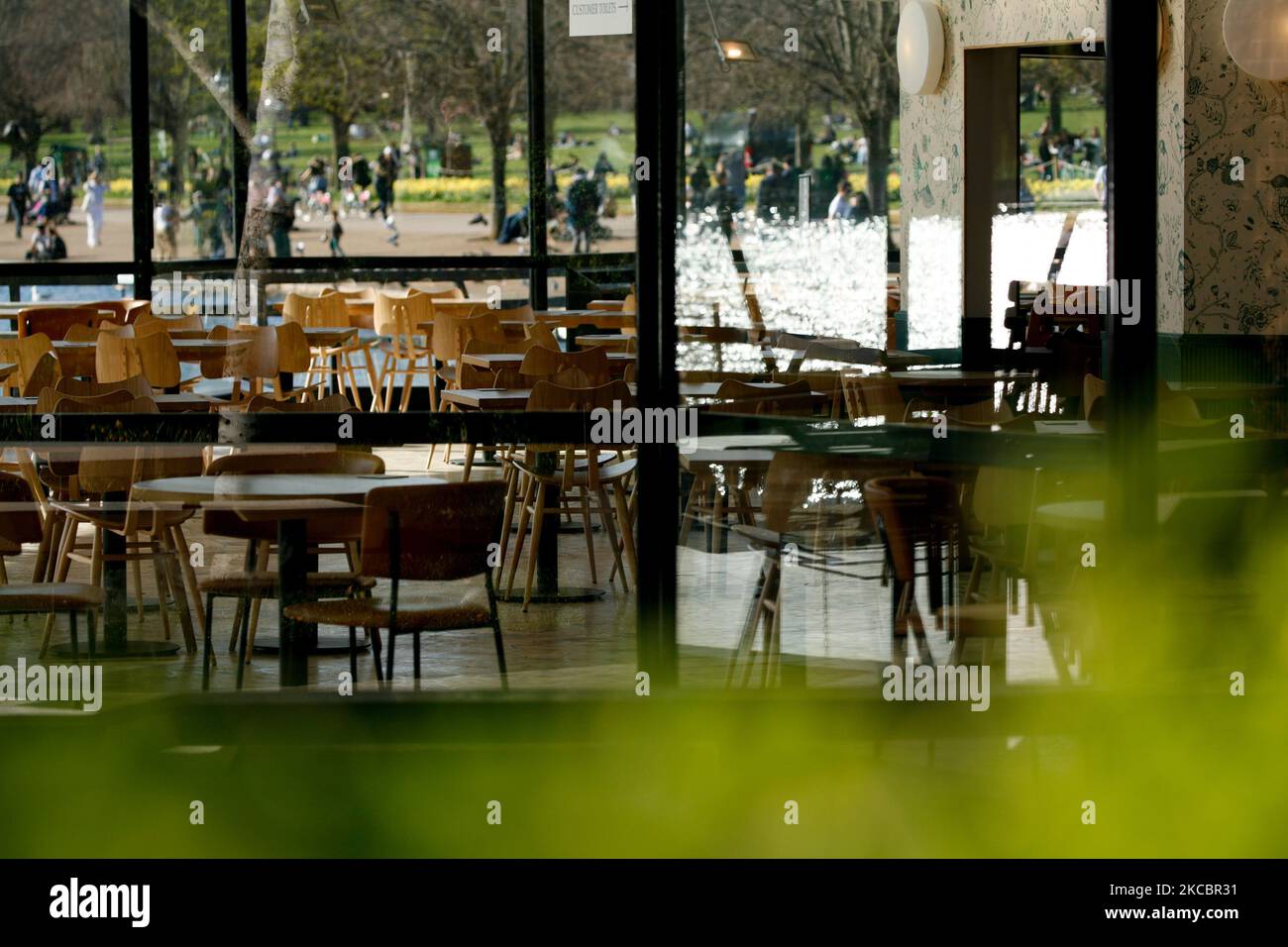 Empty tables are seen in the indoor area of a temporarily-closed cafe beside the Serpentine lake in Hyde Park in London, England, on March 29, 2021. Lockdown restrictions were eased across England today, with the 'stay home' rule ended, groups of up to six allowed to meet outside, outdoor sports restarted and weddings with up to six people attending permitted to go ahead. Shops, hospitality and leisure businesses remain closed however, with the next relaxation of restrictions not due until April 12 at the earliest. Today's easing has meanwhile coincided with the first of a three-day 'mini-heat Stock Photo