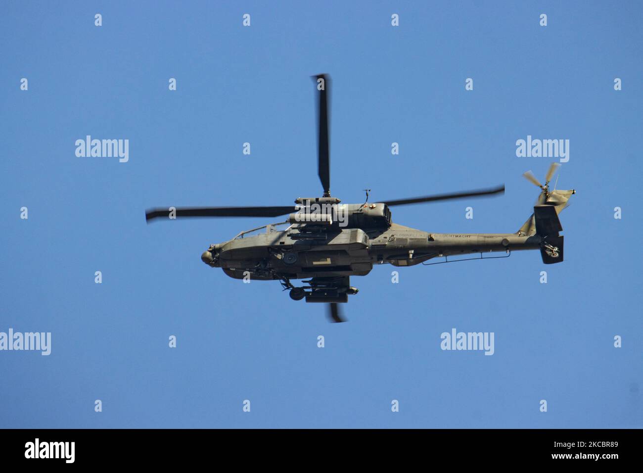 Royal Netherlands Air Force RNLAF or Koninklijke Luchtmacht in Dutch, AH-64 Apache attacking helicopter of the Army, as seen flying in the blue sky, during an exercise mission near the airport of Eindhoven. The American Made iconic Apache helicopter AH-64 is a military attack helicopter carrying multiple sensors and weapon systems like Hellfire missiles, Hydra rockets with night vision capability. The U.S. Army is the primary operator but also Greece, Japan, Isreal, Netherlands, Singapore and United Arab Emirates, while the helicopter served in conflict areas or war in Panama, Kosovo, Afghanis Stock Photo