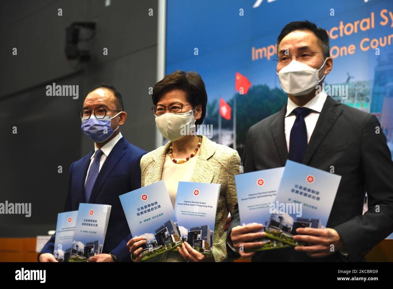 From Left to Right Mr. Eric Tsang Secretary for Constitutional and Mainland Affairs , Ms Carrie Lam Hong Kong Chief Executive , Mr Roy Tang Permanent Secretary for Constitutional and Mainland Affairs, holds a booklet while posing for a photo before a press conference in Hong Kong, Tuesday, March 30, 2020. The National People's Congress Standing Committee (NPCSC) on Tuesday approved amendments to annexes 1 and 2 of Hong Kong's Basic Law to pave the way for a drastic overhaul of the SAR's electoral system, local member Tam Yiu-chung said One of the major revamps includes expanding the role of th Stock Photo