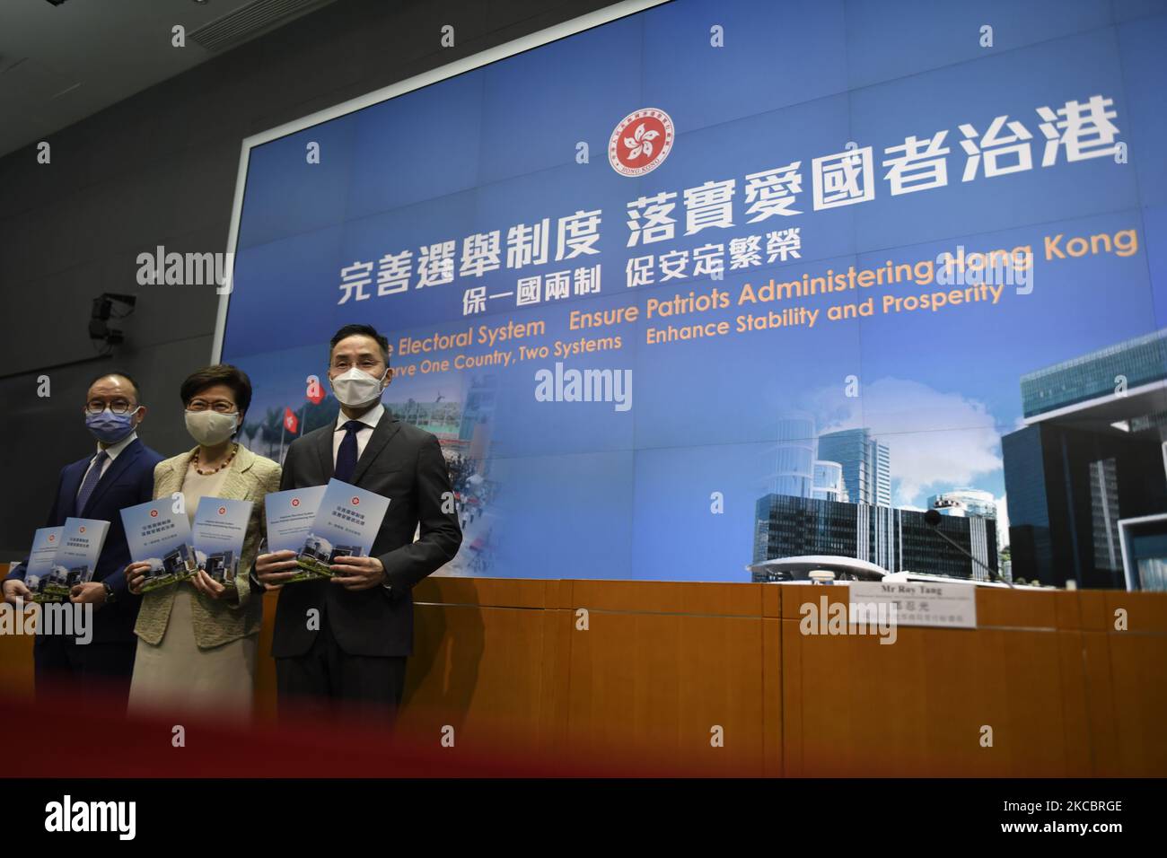 From Left to Right Mr. Eric Tsang Secretary for Constitutional and Mainland Affairs , Ms Carrie Lam Hong Kong Chief Executive , Mr Roy Tang Permanent Secretary for Constitutional and Mainland Affairs, holds a booklet while posing for a photo before a press conference in Hong Kong, Tuesday, March 30, 2020. The National People's Congress Standing Committee (NPCSC) on Tuesday approved amendments to annexes 1 and 2 of Hong Kong's Basic Law to pave the way for a drastic overhaul of the SAR's electoral system, local member Tam Yiu-chung said One of the major revamps includes expanding the role of th Stock Photo