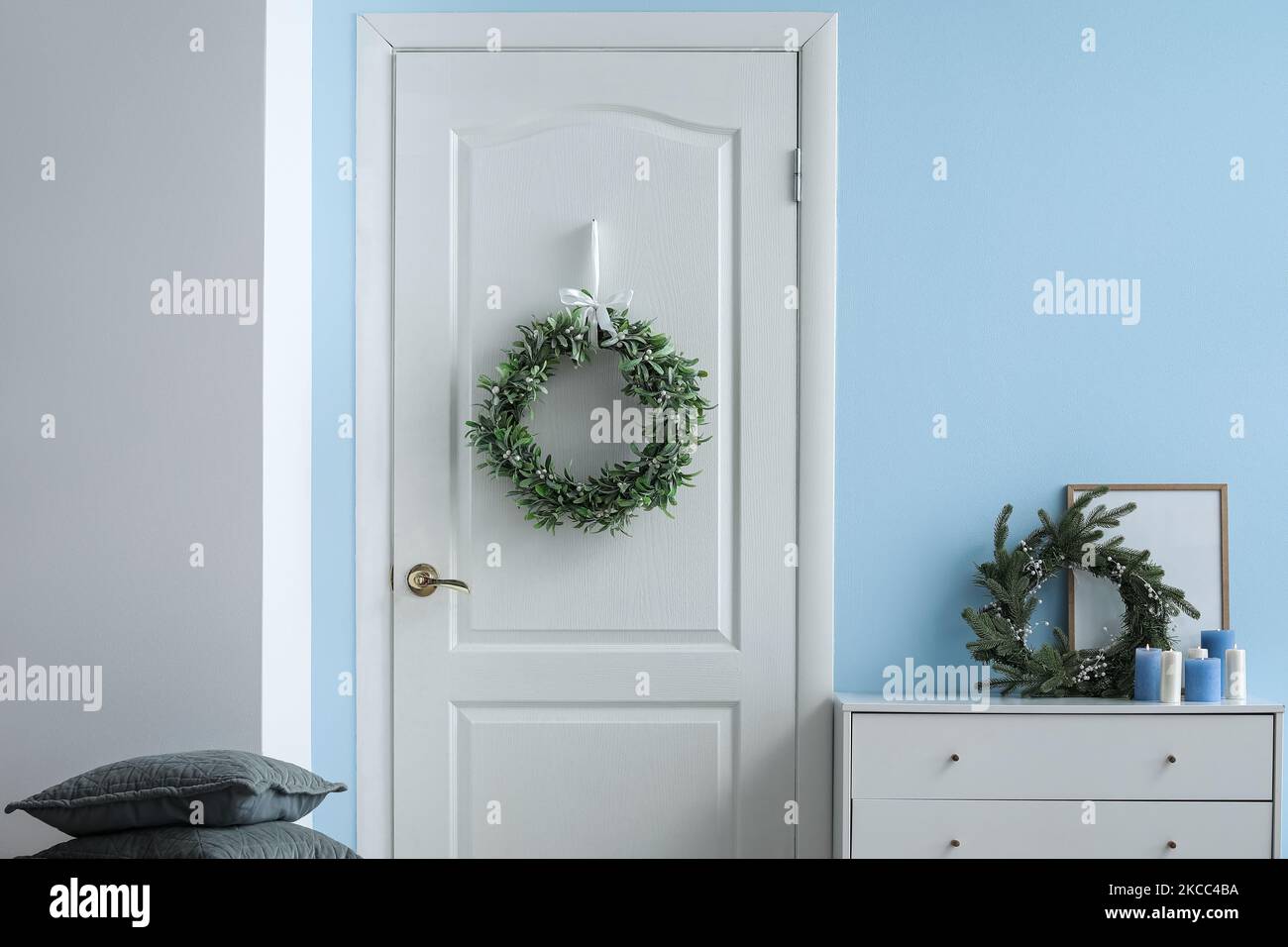 Stylish Christmas mistletoe wreath hanging on door in room Stock Photo