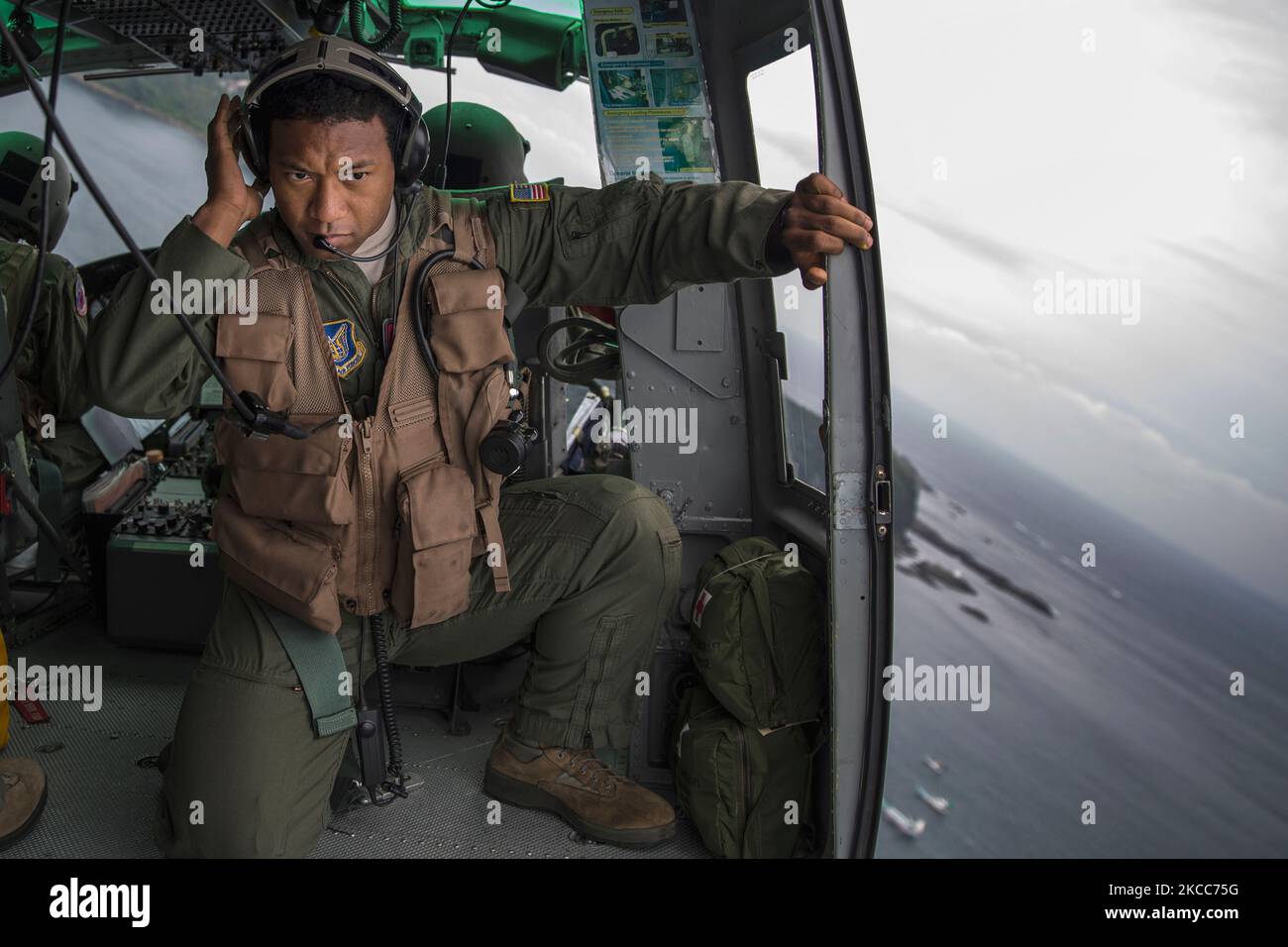 An airman listens to the radio in a UH-1N Iroquois over Japan. Stock Photo