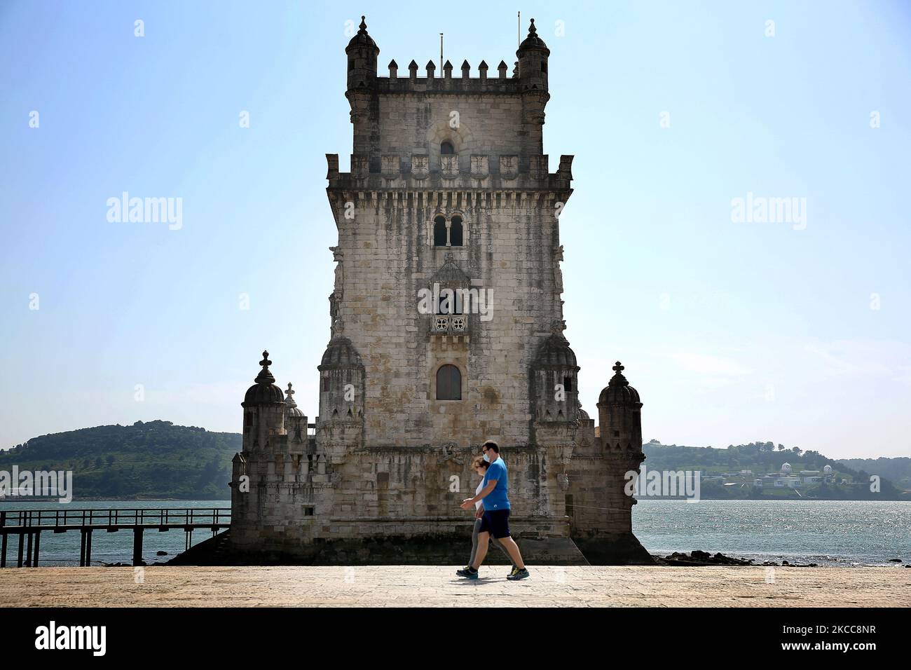 People wearing face masks walk past the Belem Tower in Lisbon, Portugal, on April 5, 2021. Portugal started on April 5, the second phase of lifting COVID-19 restrictions, with the reopening of cafes and restaurants terraces, museums, monuments, gyms, shops up to 200 square meters, and the return to classes of students from the 5th to the 9th grade, nearly two months after tightening Covid-19 curbs following a wave of cases early this year. (Photo by Pedro FiÃºza/NurPhoto) Stock Photo