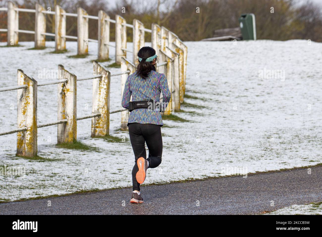 A woman as seen running near the snow. The Netherlands wakes up snow covered after an intense morning snowfall, a bizzar event for April. The second day of low temperatures and snowfall in the Netherlands after the 'White Easter' Monday with a significant drop of temperature, reaching freezing point according to Dutch meteorological agency KNMI making Easter Monday one of the coldest ever days with low temperatures recorded. Additional to the snow, hail and high speed strong ice cold wind occurred. The KNMI has issued a code yellow weather warning for Monday evening, saying there will be stron Stock Photo