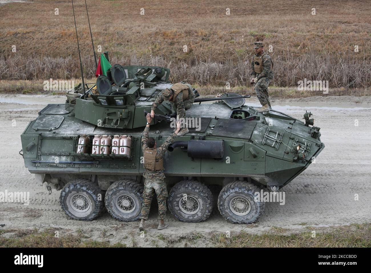 A light-armored vehicle crewman hands fellow crewman a M240B machine gun. Stock Photo