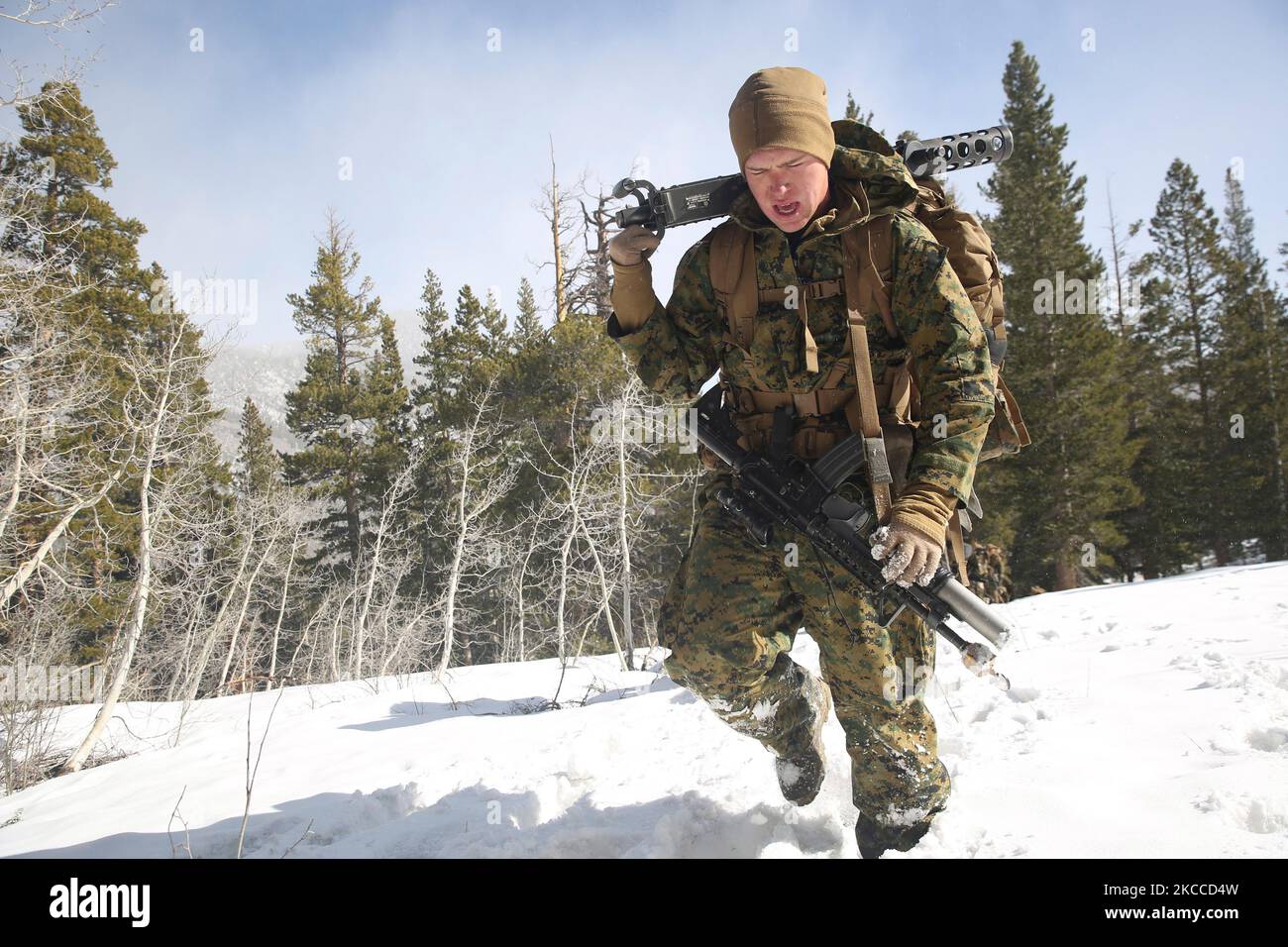 U.S. Marine carries the receiver of a .50 caliber machine gun as he trudges through snow. Stock Photo
