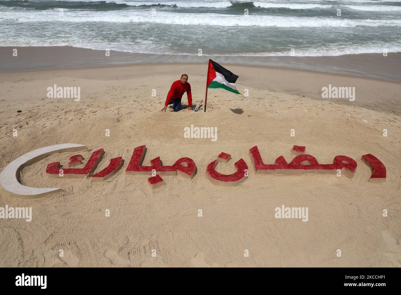 Palestinian artist Mohammed Totah works on a sand sculpture that reads in Arabic 'Ramadan Mubarak' ahead of the Muslim holy month of Ramadan, amid the coronavirus disease (COVID-19) outbreak, at a beach in Gaza City on April 11, 2021. (Photo by Majdi Fathi/NurPhoto) Stock Photo