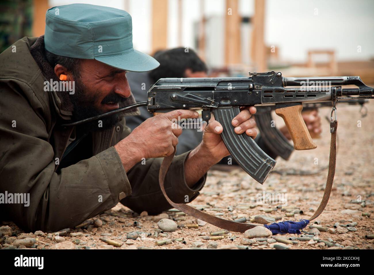 An Afghan National Police officer fires his AK-47 rifle. Stock Photo
