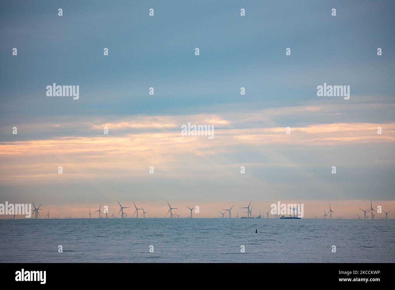 Off-shore wind park of windmills generating green renewable electric energy 20 kilometers away from the Dutch coast between the Netherlands and the United Kingdom during dusk sunset time, with clouds and ships over the horizon of the sea. The wind turbine generators create sustainable green energy from the wind power, jet stream of air in the atmosphere, the park installed in the North Sea as seen from Oosterschelde in Zeeland in the Netherlands on April 10, 2021 (Photo by Nicolas Economou/NurPhoto) Stock Photo