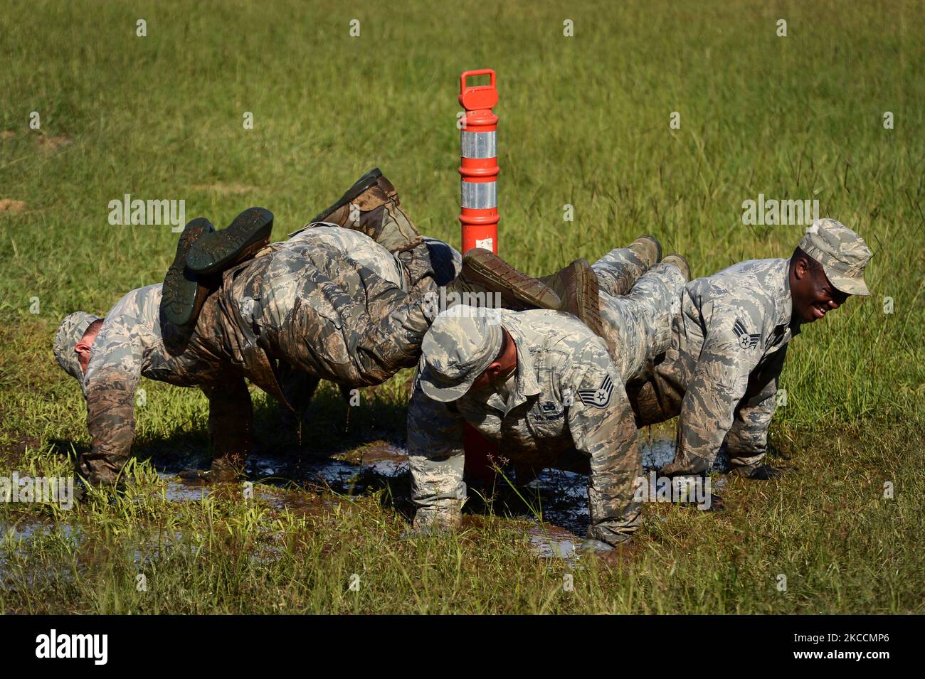 Airmen perform a four-man push-up in a puddle of mud. Stock Photo