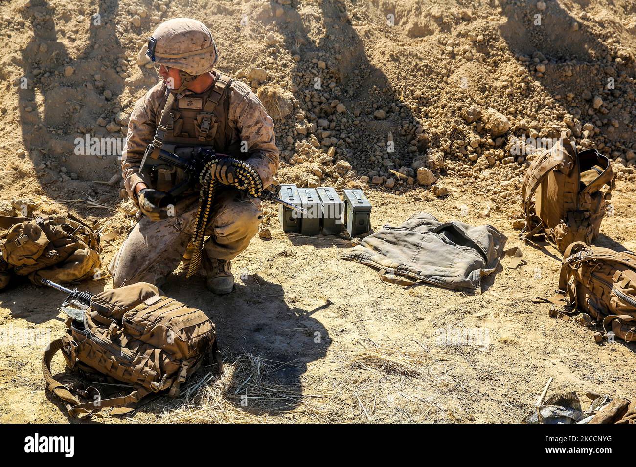 U.S. Marine picks up rounds to resupply a machine gunner. Stock Photo