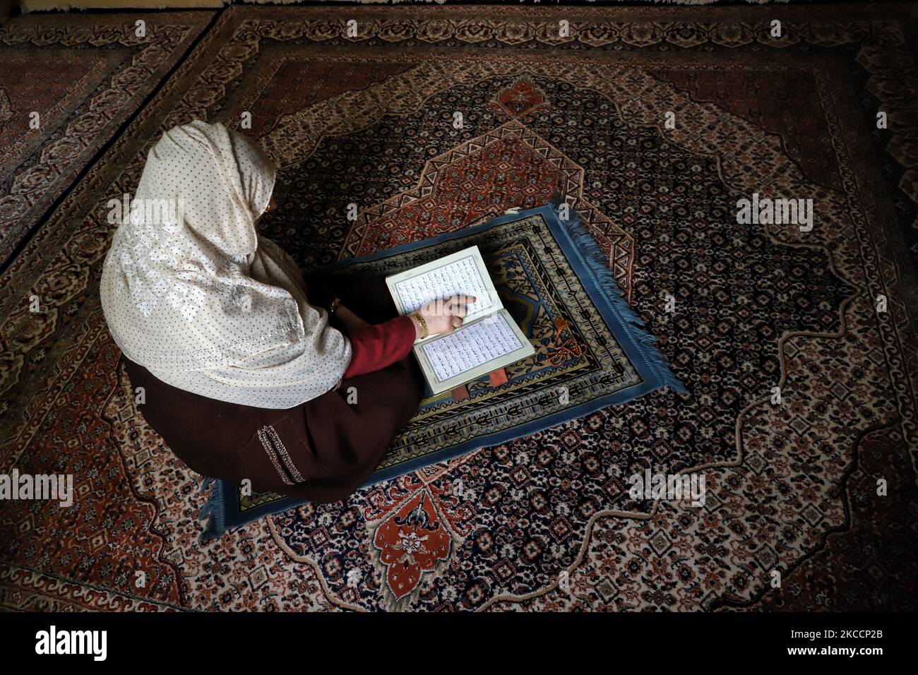 A Woman reciting holy book of Quran on the 1st day of the Holy month of Ramadan at her home amid COVID-19 Coronavirus pandemic in Sopore, District Baramulla, jammu and Kashmir, India on 14 April 2021. (Photo by Nasir Kachroo/NurPhoto) Stock Photo