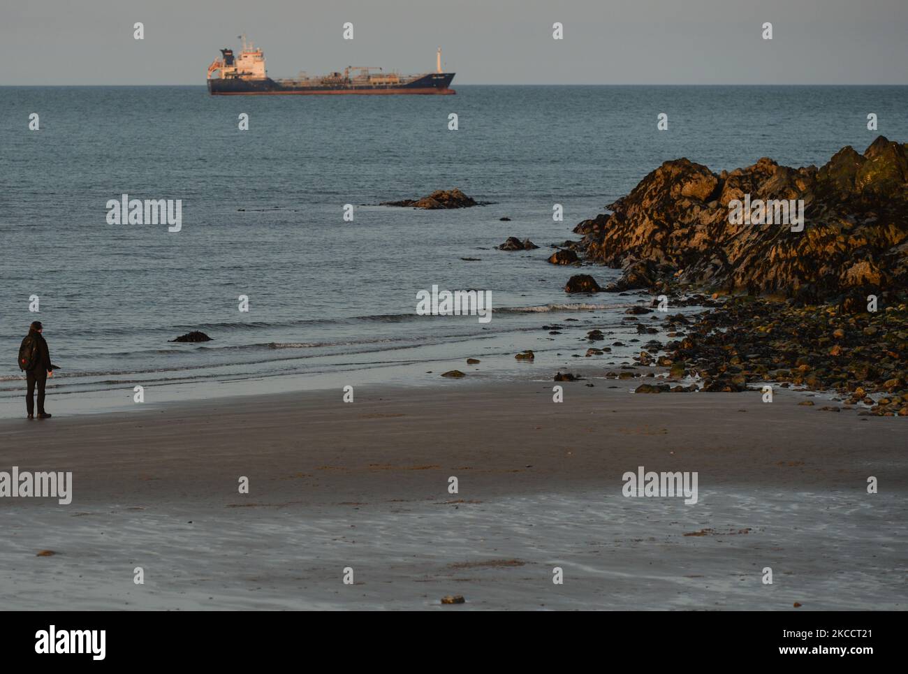 A man watches a boat in the sea near Bray's rocky beach at sunset, during the COVID-19 lockdown. On Thursday, 15 April 2021, in Bray, County Wicklow, Ireland. (Photo by Artur Widak/NurPhoto) Stock Photo