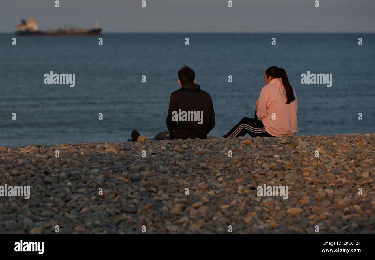 A couple watch a boat in the sea near Bray's rocky beach at sunset, during the COVID-19 lockdown. On Thursday, 15 April 2021, in Bray, County Wicklow, Ireland. (Photo by Artur Widak/NurPhoto) Stock Photo