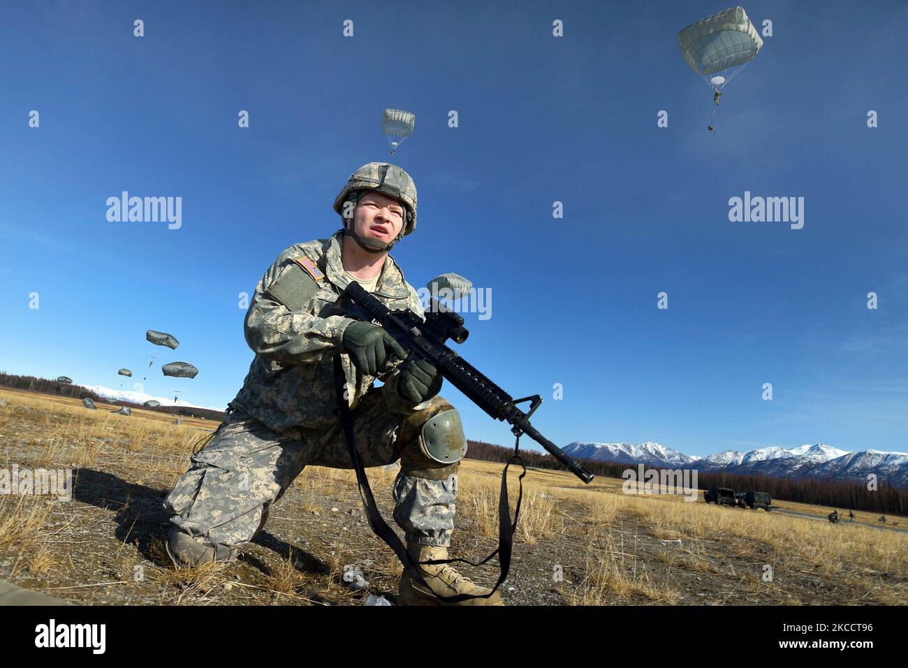 U.S. Army Soldier pulls security as paratroopers conduct a parachute assault. Stock Photo