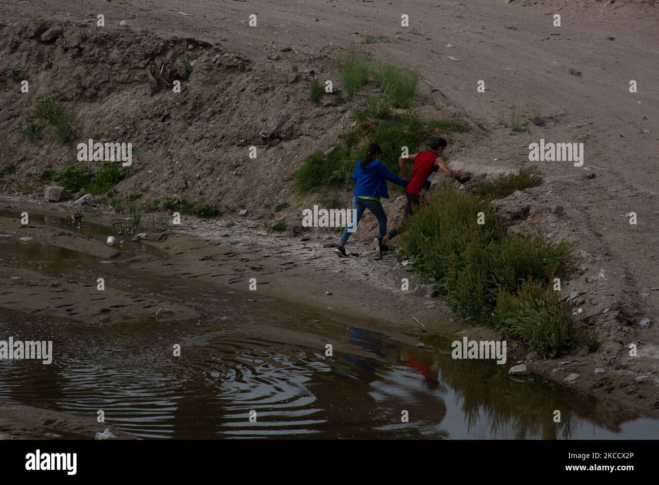 A migrant couple cross the Rio Grande in an attempt to reach the US, near the El Paso border crossing, in Ciudad Juarez, Chihuahua state, Mexico on April 14, 2021. Hundreds of migrants cross illegally into the United States, some hire criminals to help them cross illegally, others simply turn themselves in to the border patrol to try to apply for political asylum (Photo by David Peinado/NurPhoto) Stock Photo