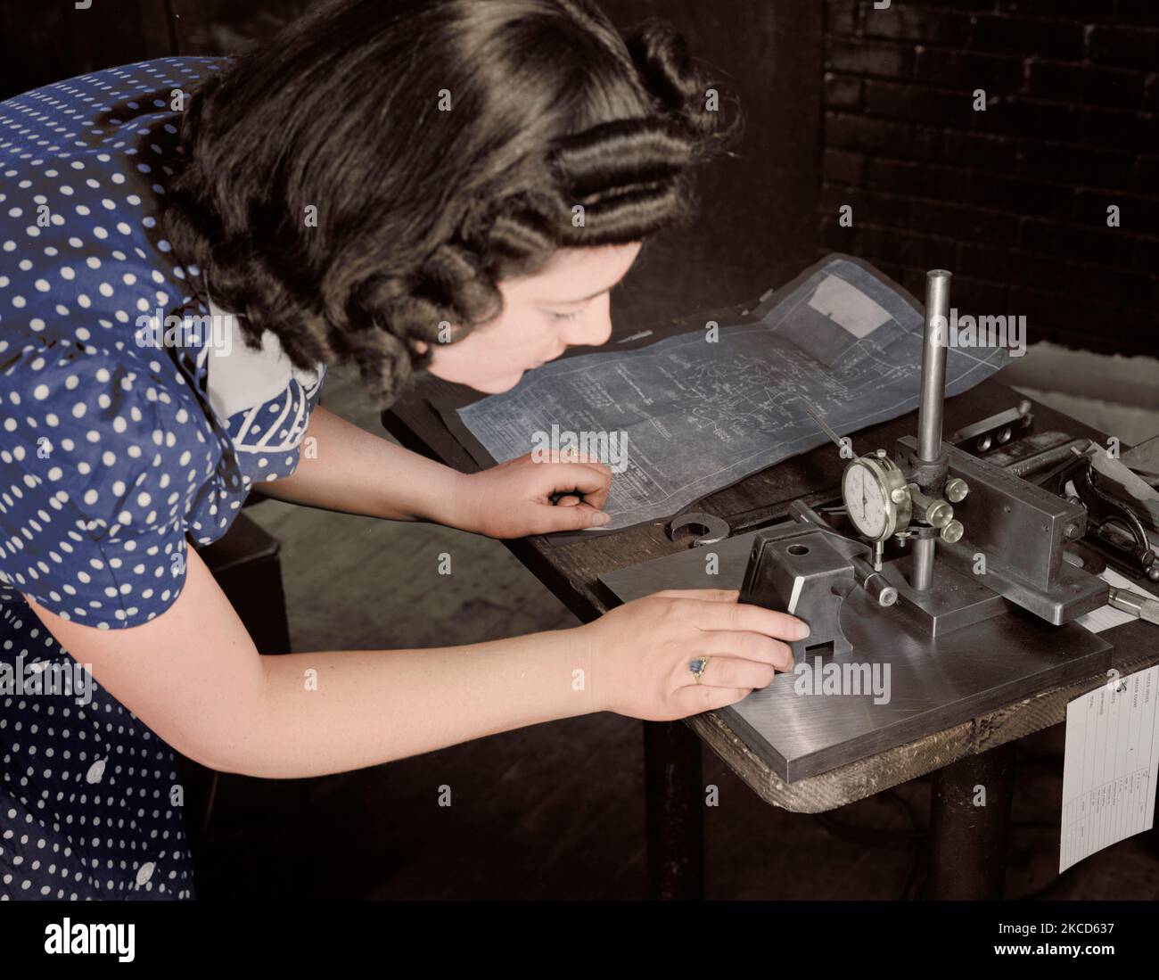 Woman factory worker checks completed V-blocks with blueprint specification, 1942. Stock Photo