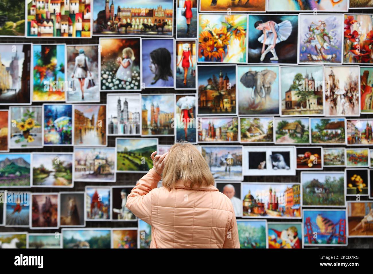 A woman looks at the paintings on the street gallery in Krakow, Poland on April 18, 2021. (Photo by Jakub Porzycki/NurPhoto) Stock Photo