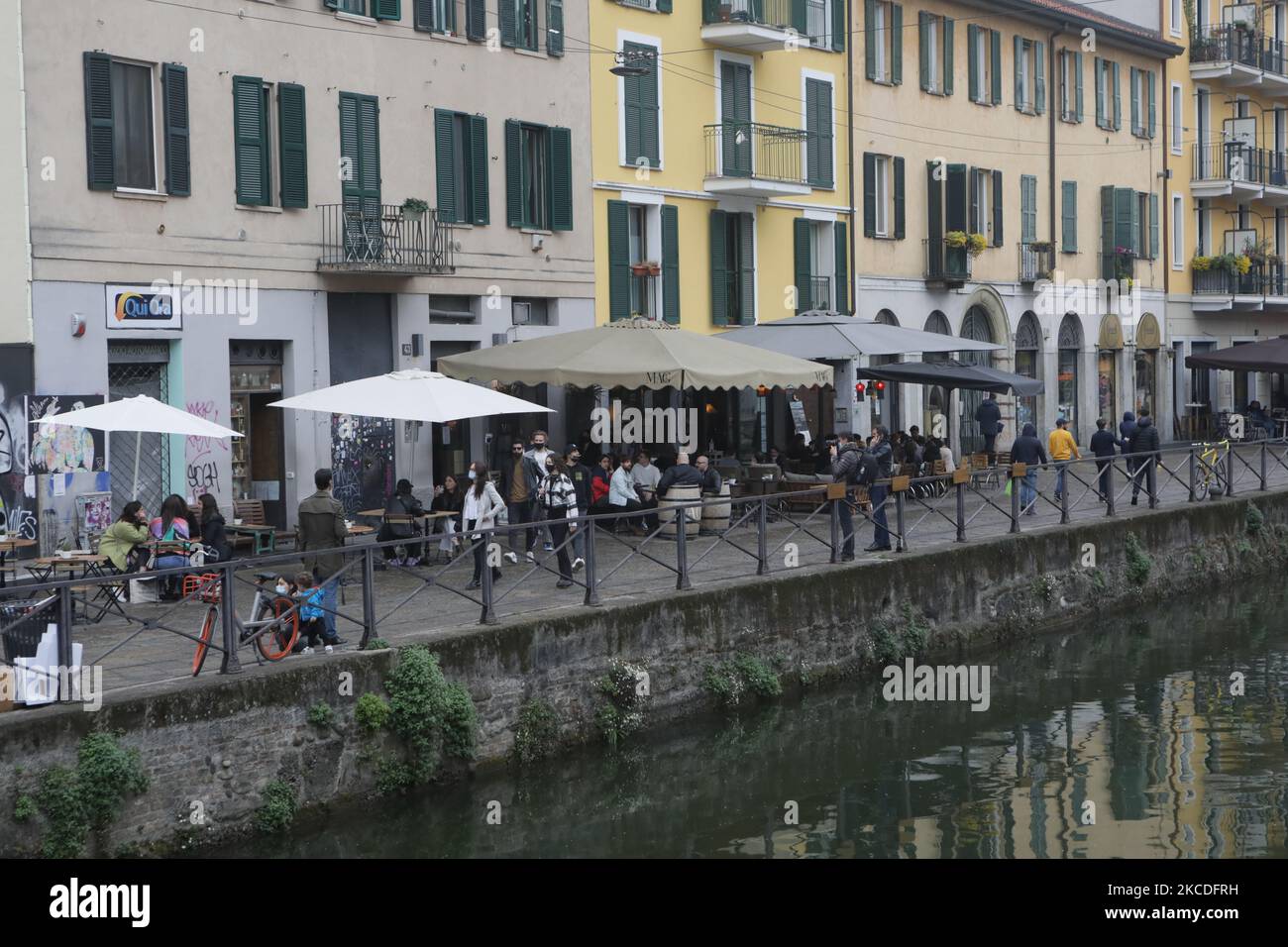 People have a drink on a bar terrace at the Navigli in downtown Milan, Italy on April 26, 2021 as bars, restaurants, cinemas and concert halls partially reopen across Italy in a boost for coronavirus-hit businesses, as parliament debates the government's 220-billion-euro ($266-billion) EU-funded recovery plan. - After months of stop-start restrictions imposed to manage its second and third waves of Covid-19, Italy hopes this latest easing will mark the start of something like a normal summer. (Photo by Mairo Cinquetti/NurPhoto) Stock Photo