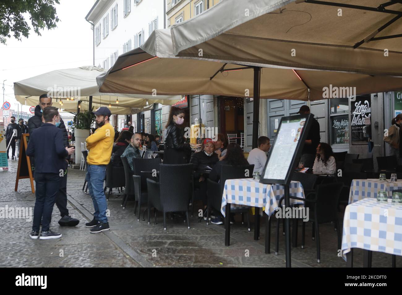 People have a drink on a bar terrace at the Navigli in downtown Milan, Italy on April 26, 2021 as bars, restaurants, cinemas and concert halls partially reopen across Italy in a boost for coronavirus-hit businesses, as parliament debates the government's 220-billion-euro ($266-billion) EU-funded recovery plan. - After months of stop-start restrictions imposed to manage its second and third waves of Covid-19, Italy hopes this latest easing will mark the start of something like a normal summer. (Photo by Mairo Cinquetti/NurPhoto) Stock Photo