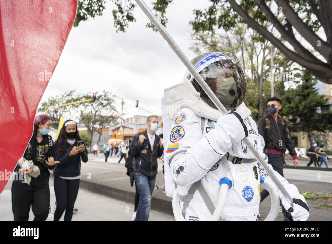A man in biosafety clothing holds a flag during a national strike in Bogota, Colombia, on April 28, 2021 to protest against the tax reform presented by the colombian government of Ivan Duque. The protest was accompanied by the differents groups of teachers, workers and students that doesn?t agree with the decisions of the government, the protest had all the COVID protocols, They seek to sink a tax reform which proposes elimination of VAT free goods.while the country is passing by the third wave of the pandemic virus. (Photo by David Rodriguez/NurPhoto) Stock Photo