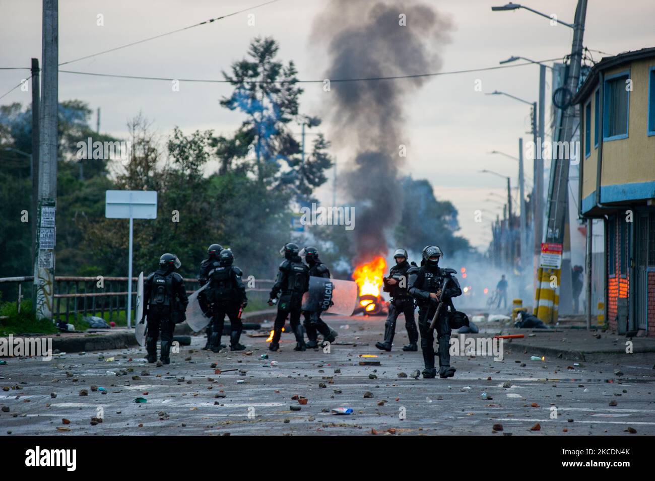 Riot police officers stand behind fire as clashes and riots between ...