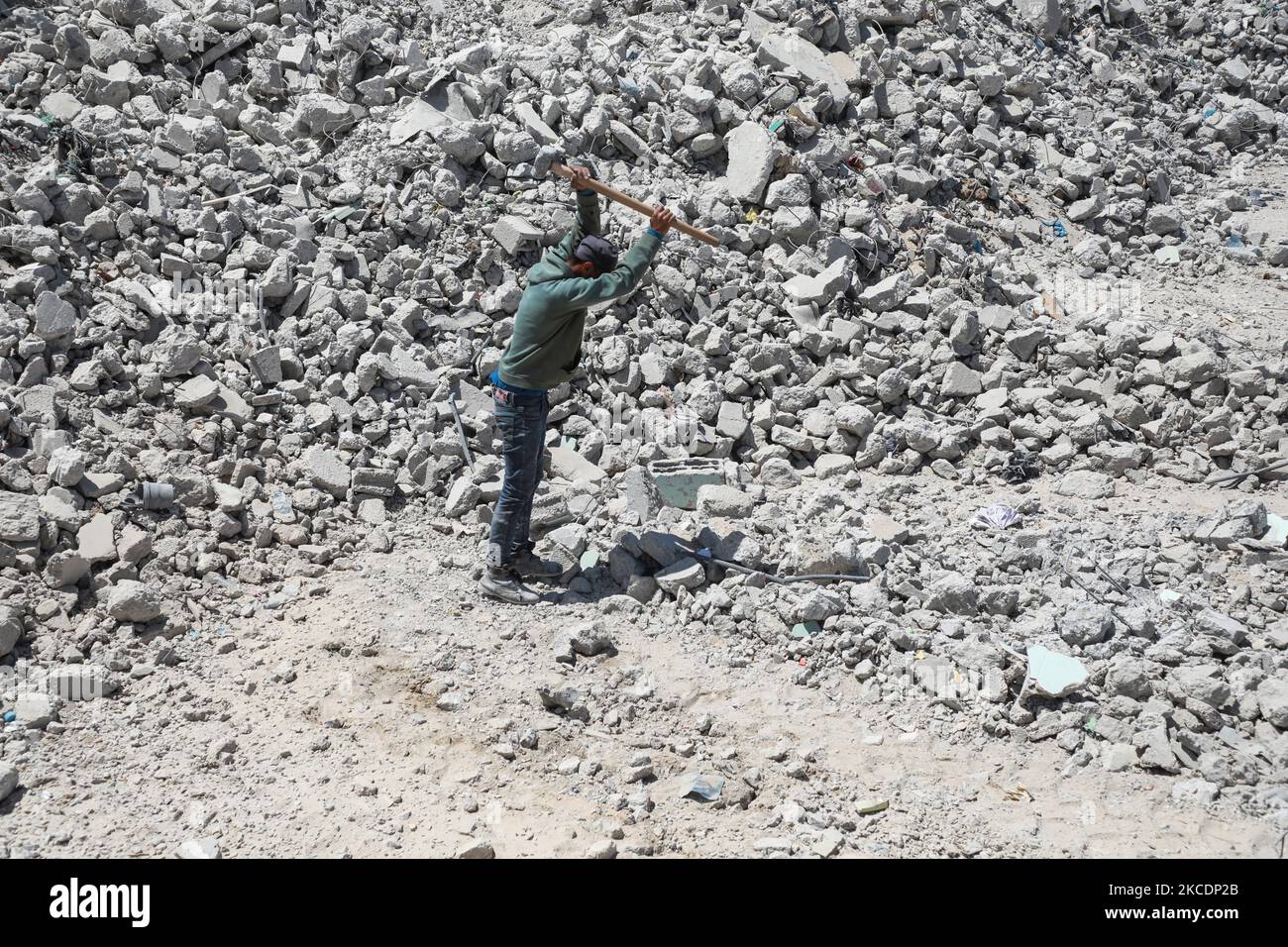 A Palestinian worker uses a sledgehammer to break concrete blocks at a