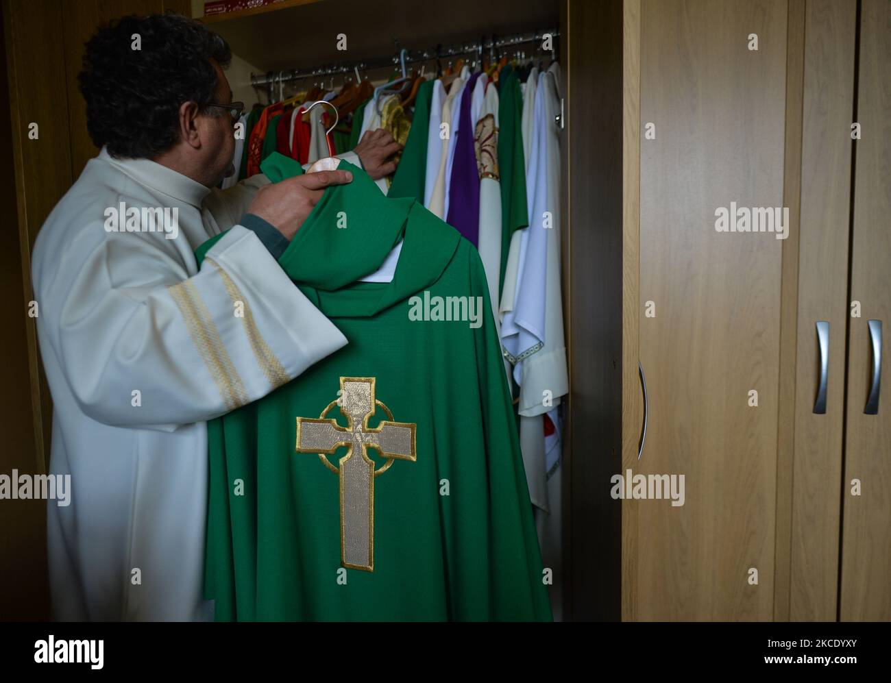 Father Krzysztof Sikora inspects the chasuble in the sacristy of the Roman Catholic Church 'Our Lady Star Of The Sea' in Roundstone, Connemara. Geographically, Roundstone parish is considered Ireland's largest parish and stretches from the Gurteen Beaches to the Twelve Bens and Mám Tuirc Mountains. Until the 1990s, the parish was served by three priests, now there is only one to look after five churches. The current Parish Priest, a Polish born Fr Krzysztof Sikora, is a member of the religious congregation of the Divine Word Missionaries. After years of working as a missionary in the Philippin Stock Photo