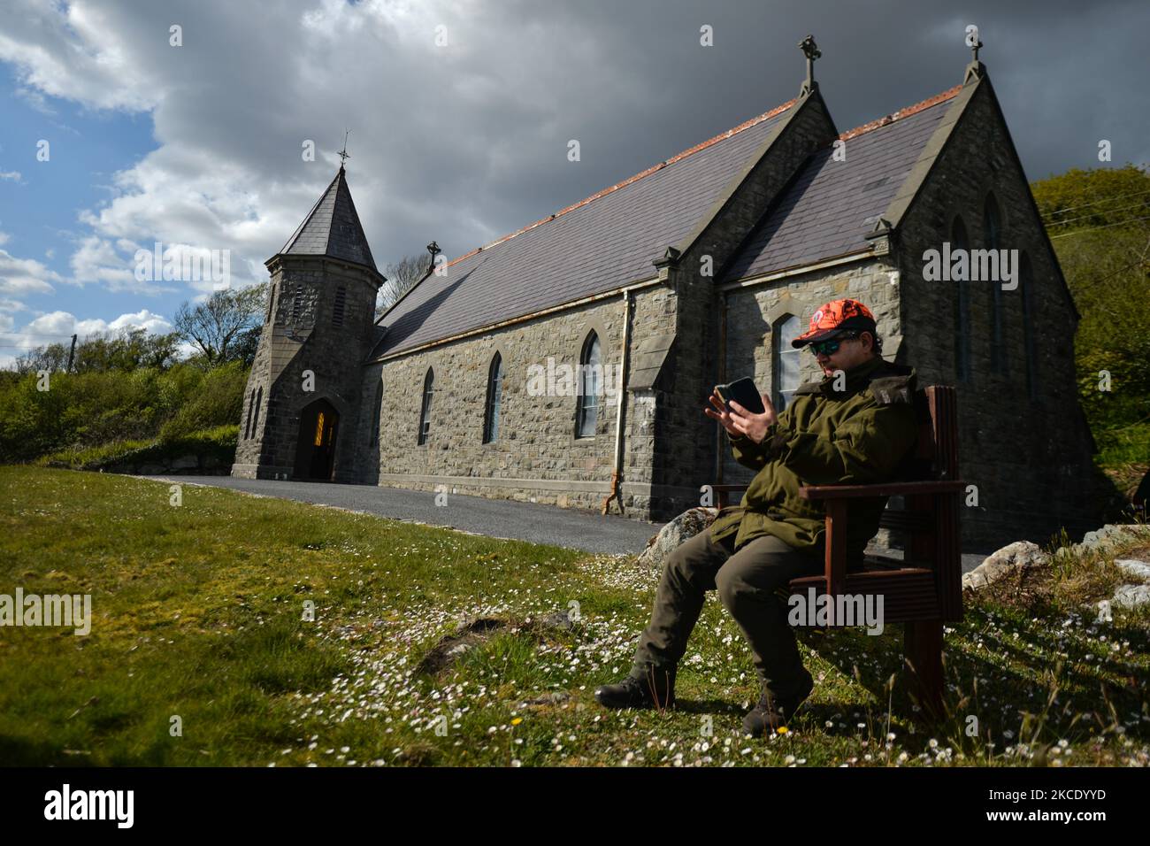 Father Krzysztof Sikora checks his mobile phone outside St James's Church, in Cashel, Connemara. Geographically, Roundstone parish is considered Ireland's largest parish and stretches from the Gurteen Beaches to the Twelve Bens and Mám Tuirc Mountains. Until the 1990s, the parish was served by three priests, now there is only one to look after five churches. The current Parish Priest, a Polish born Fr Krzysztof Sikora, is a member of the religious congregation of the Divine Word Missionaries. After years of working as a missionary in the Philippines, Germany and Poland, he settled in Ireland i Stock Photo