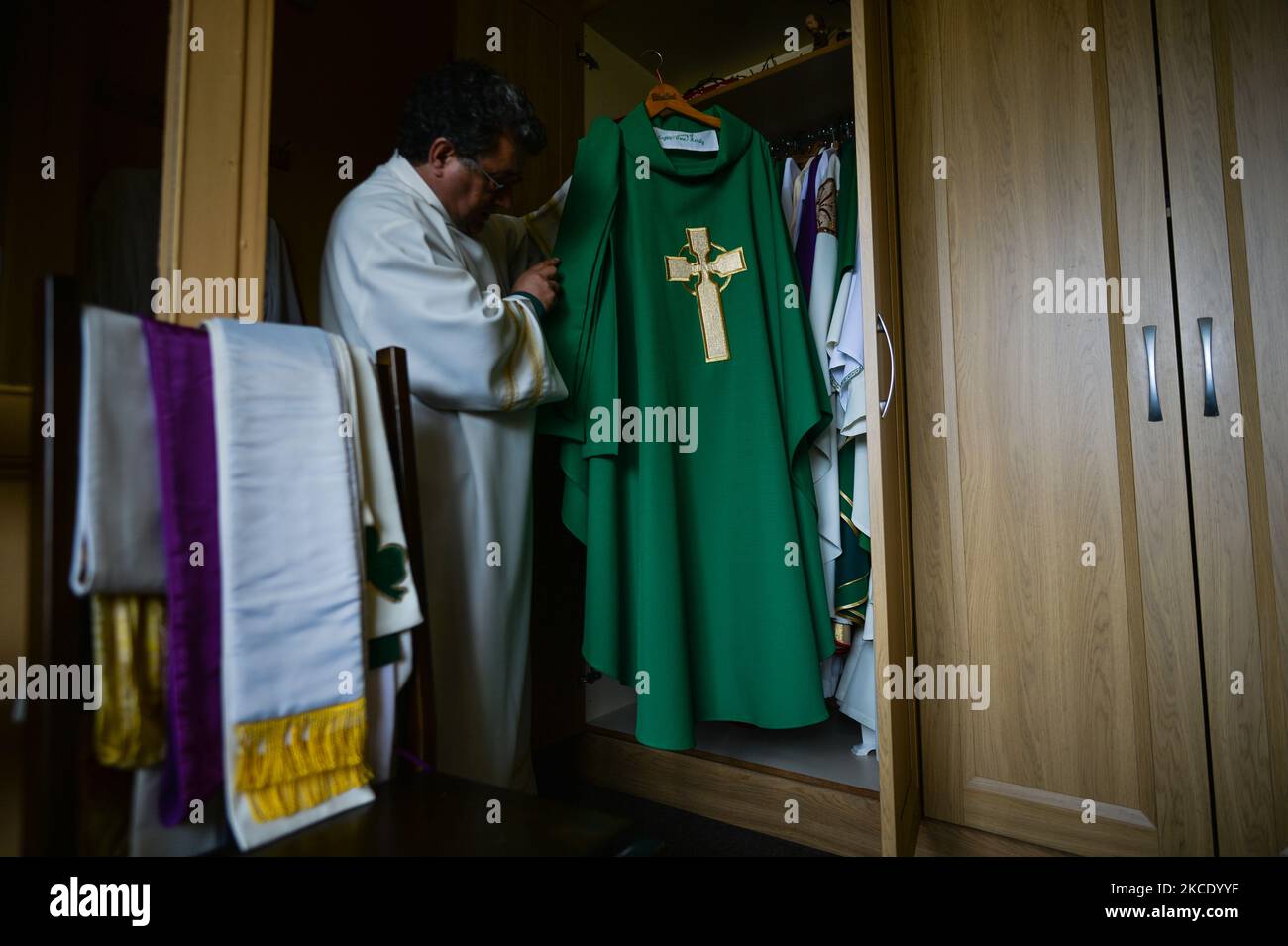 Father Krzysztof Sikora inspects the chasuble in the sacristy of the Roman Catholic Church 'Our Lady Star Of The Sea' in Roundstone, Connemara. Geographically, Roundstone parish is considered Ireland's largest parish and stretches from the Gurteen Beaches to the Twelve Bens and Mám Tuirc Mountains. Until the 1990s, the parish was served by three priests, now there is only one to look after five churches. The current Parish Priest, a Polish born Fr Krzysztof Sikora, is a member of the religious congregation of the Divine Word Missionaries. After years of working as a missionary in the Philippin Stock Photo