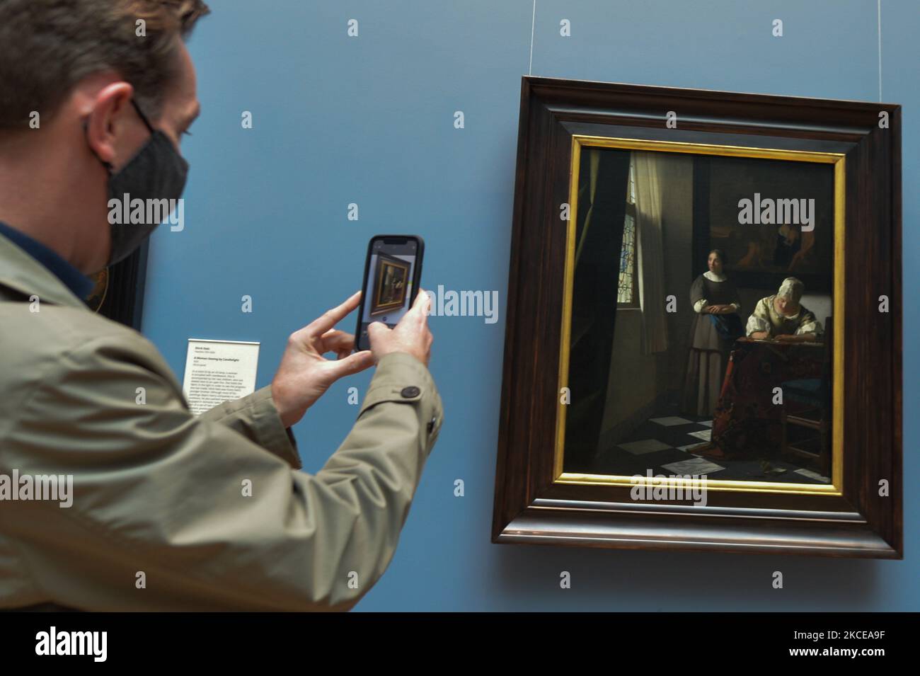 Irish TV presenter Ryan Tubridy takes a photo of an oil painting 'Woman Writing a Letter, with her Maid' by Johannes Vermeer inside the National Gallery of Ireland in Dublin. After five months of strict lockdown, the first stage of defrosting the Irish economy and loosening of restrictions is taking place. From today, the Inter-county travel is permitted. Galleries, museums and libraries, hairdressers and barbers can reopen. The main changes also concern non-essential retail by appointments, easing of the rules around outdoor meetings and the resumption of religious worship in churches. On Mon Stock Photo