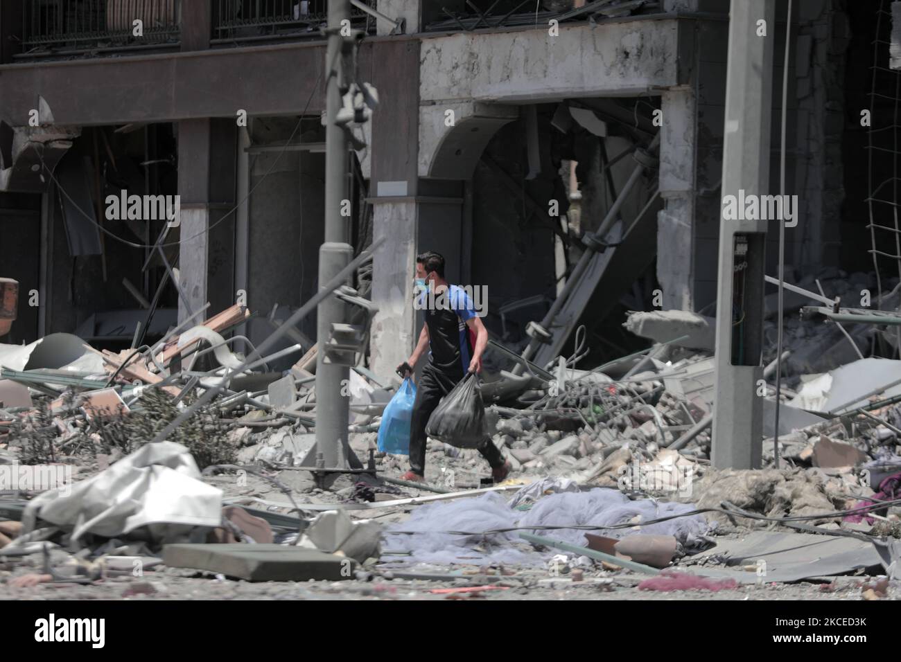 A Palestinian man walks at the rubble of the severely damaged Al-Jawhara Tower in Gaza City on May 12, 2021 after it was hit by Israeli airstrikes amid the escalating flare-up of Israeli-Palestinian violence. The Health Ministry in the Hamas-run Gaza Strip said the number of Palestinians killed has risen to 35, including 12 children, while 233 people were reported injured. (Photo by Momen Faiz/NurPhoto) Stock Photo