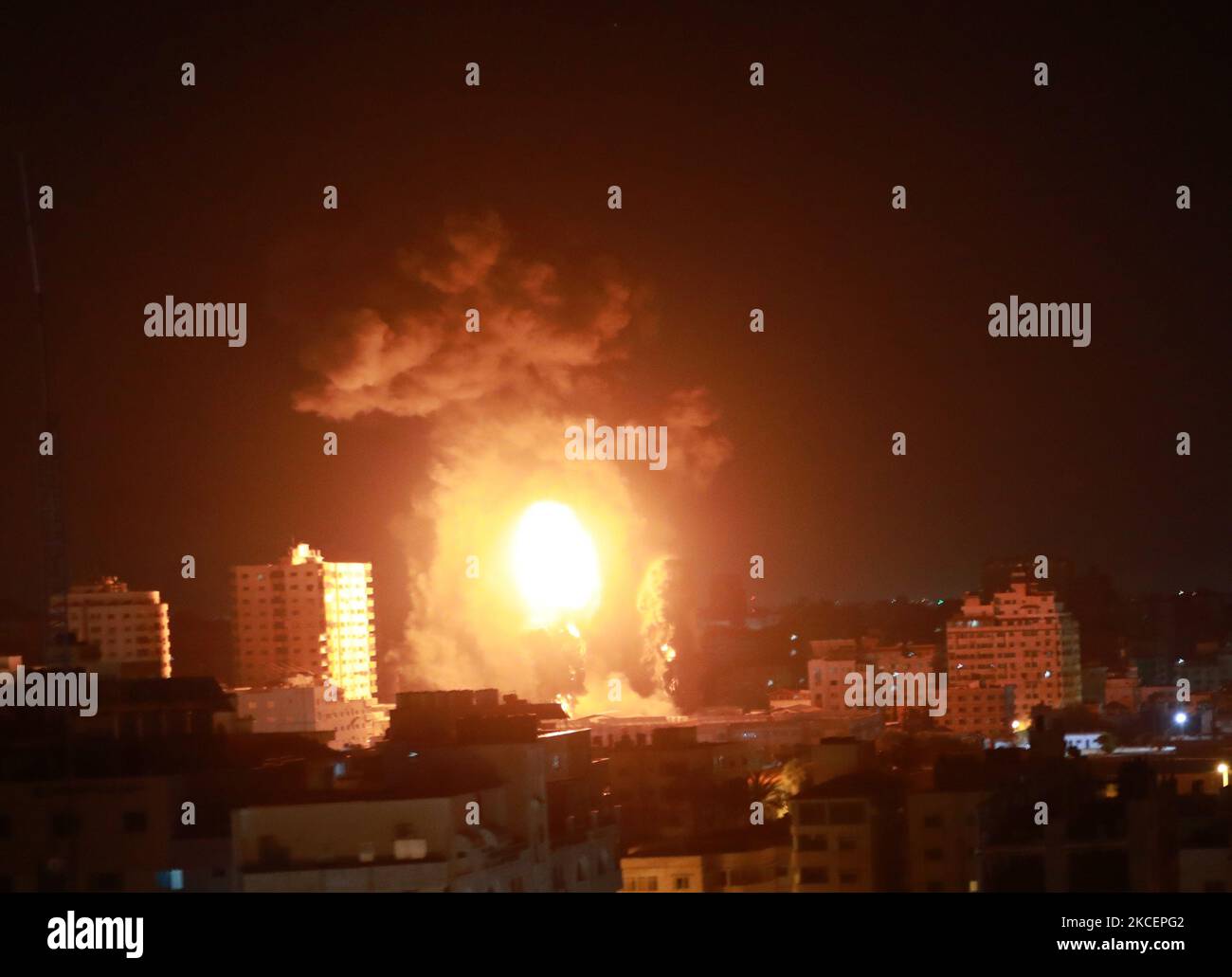 A ball of fire and a plume of smoke rise above buildings in Gaza City as Israeli forces shell the Palestinian enclave, early on May 17, 2021. (Photo by Majdi Fathi/NurPhoto) Stock Photo