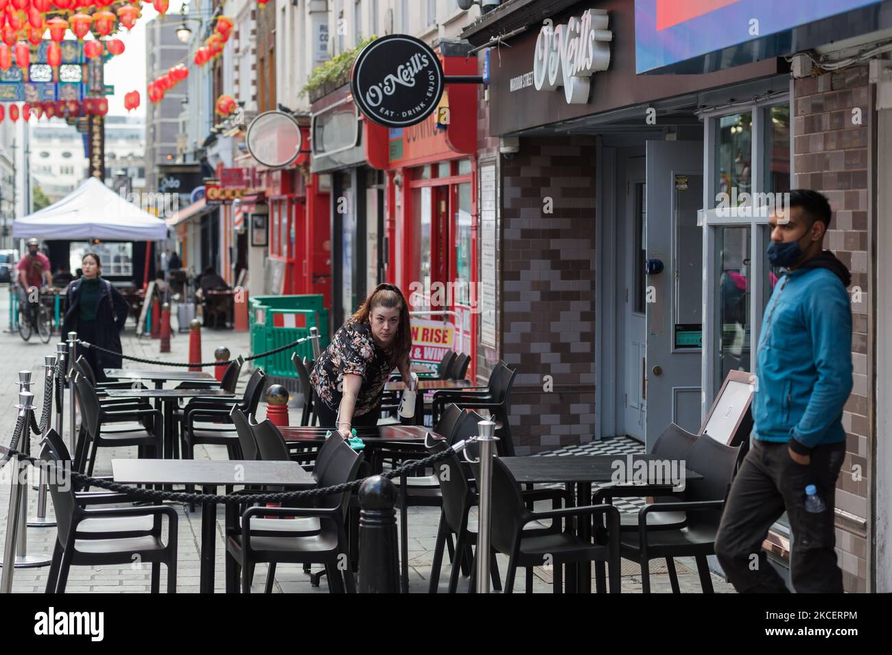 LONDON, UNITED KINGDOM - MAY 17, 2021: A waiter prepares tables outside a restaurant in Soho as England moves to Step 3 in easing of coronavirus restrictions, on 17 May, 2021 in London, England. From today indoor hospitality and entertainment venues are allowed to re-open, six people or two households can meet indoors and international travel without need for quarantine resumes to 12 green list countries, however there are concerns that the surge in cases of the Indian Covid variant may delay the fourth stage of easing lockdown on June 21. (Photo by WIktor Szymanowicz/NurPhoto) Stock Photo