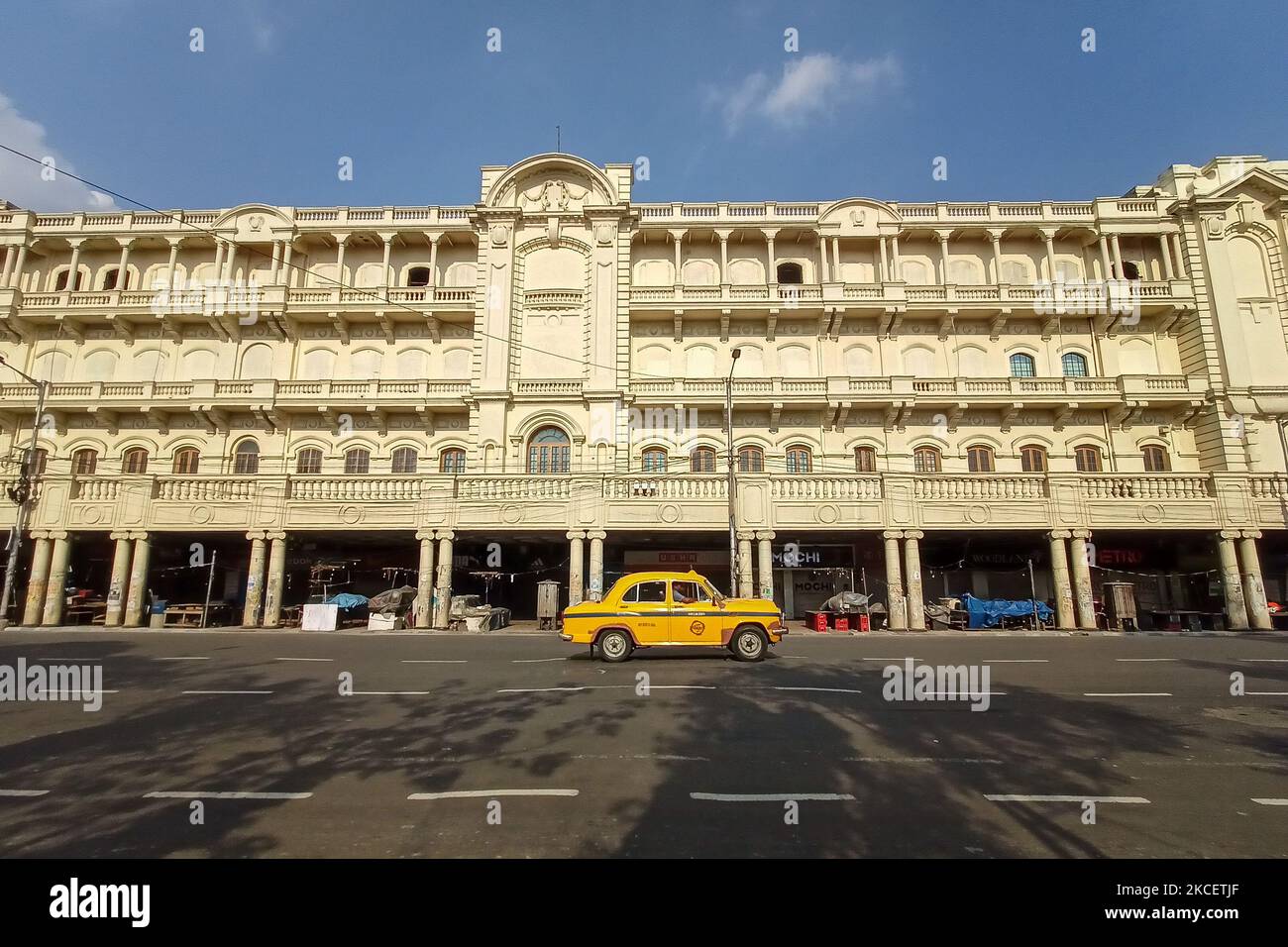 A yellow taxi drives by a closed hotel and shopping stores at a shopping hub in Kolkata , India , on 18 may 2021 , during 1r4 day lockdown in West Bengal. (Photo by Debarchan Chatterjee/NurPhoto) Stock Photo