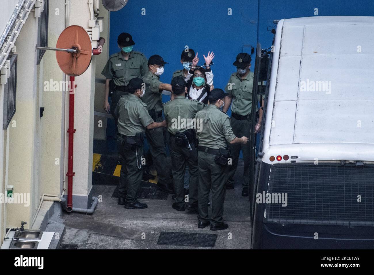 Pro-Democracy Activists Figo Chan Holds up his hands with handcuffs on it while correction department officers escort him form a van to the Lai Chi Kwok Reception Center in Hong Kong, Tuesday, May 18, 2021. A Judge refused to grant bail to Chan, former Democratic Party chairmen Albert Ho and Yeung Sum, activist Avery Ng, ex-lawmaker Sin Chung-kai and Richard Tsoi of the Hong Kong Alliance, They were among a group of 10 democrats who pleaded guilty on Monday to organising a demonstration on October 1, 2019, when thousands of protesters took to the streets in defiance of a police ban, sentencing Stock Photo