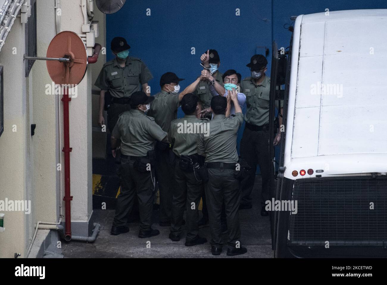 Pro-Democracy Activists Avery Ng Holds up a thumb while correction department officers escort him form a van to the Lai Chi Kwok Reception Center in Hong Kong, Tuesday, May 18, 2021. A Judge refused to grant bail to Chan, former Democratic Party chairmen Albert Ho and Yeung Sum, activist Avery Ng, ex-lawmaker Sin Chung-kai and Richard Tsoi of the Hong Kong Alliance, They were among a group of 10 democrats who pleaded guilty on Monday to organising a demonstration on October 1, 2019, when thousands of protesters took to the streets in defiance of a police ban, sentencing is scheduled for Friday Stock Photo