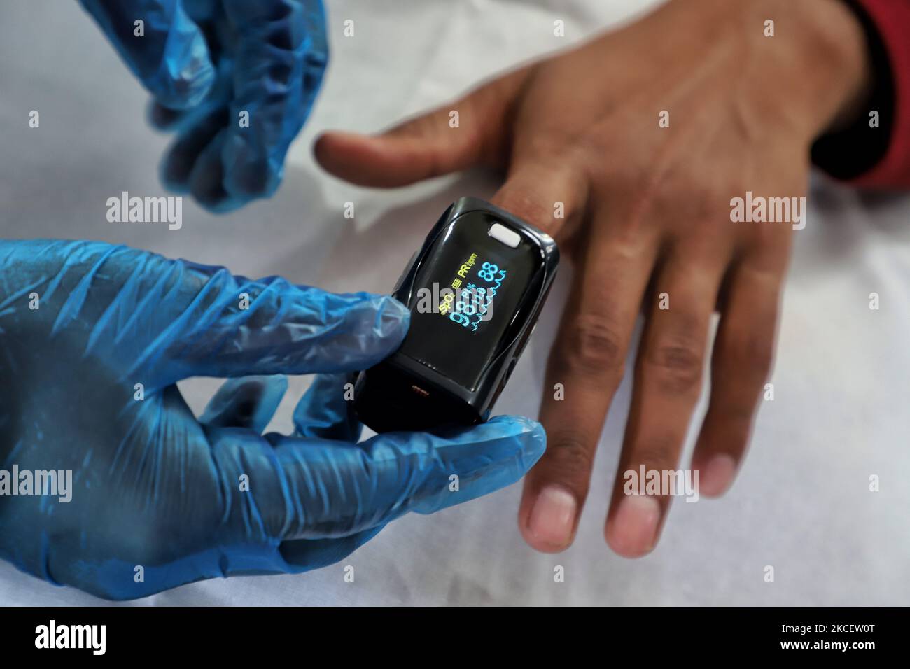 A Health worker uses Oximeter to check the Oxygen Level of a Person at a School Turned COVID-19 Center in Uri, Baramulla, Jammu and Kashmir, India on 18 May 2021. Indian Army has set-up a High Dependency Unit (HDU) hospital in Jammu and Kashmir's Baramulla. The hospital will be run in collaboration with civil administration of Baramulla district. 'To help the people in Kashmir valley, a hospital has been established in the Baramulla district. The people in Kashmir will get good medical facilities here,' Dr Paul M Varghese, Colonel Medical team Said (Photo by Nasir Kachroo/NurPhoto) Stock Photo