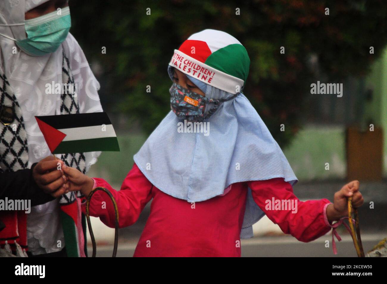 A mother gives a small Palestine flag to her child during a demonstration to defend the rights of the Palestine people against Israeli soldiers attacking the city square of Palu, Central Sulawesi Province, on May 18, 2021. Israeli soldiers' attacks on Palestine have resulted in hundreds the victims died and were injured, has provoked a lot of anger and solidarity from the Indonesian people. (Photo by Faldi Muhammad/NurPhoto) Stock Photo