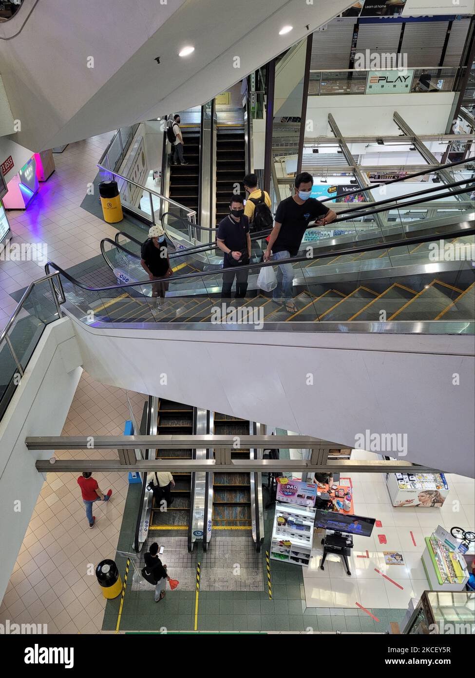 Shoppers wearing masks ride escalators in a Shopping mall in Singapore days after new lockdown measures were announced after a spike in Covid-19 cases, 20 May 2021. (Photo by Joseph Nair/NurPhoto) Stock Photo