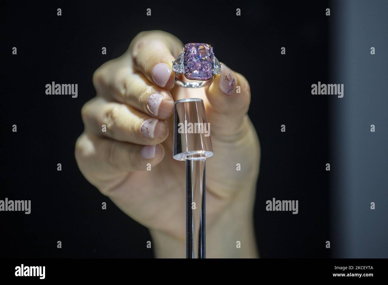 A woman holds the Sakura Diamond during preview at Christie's in Hong Kong, China, 20 May 2021. The 15.81 Carat Fancy Vivid Purple Pink Internally Flawless Type lla Diamond Ring will be auctioned in Hong Kong on 23 May 2021 for an estimated 25 million to 38 million US dollars. (Photo by Vernon Yuen/NurPhoto) Stock Photo