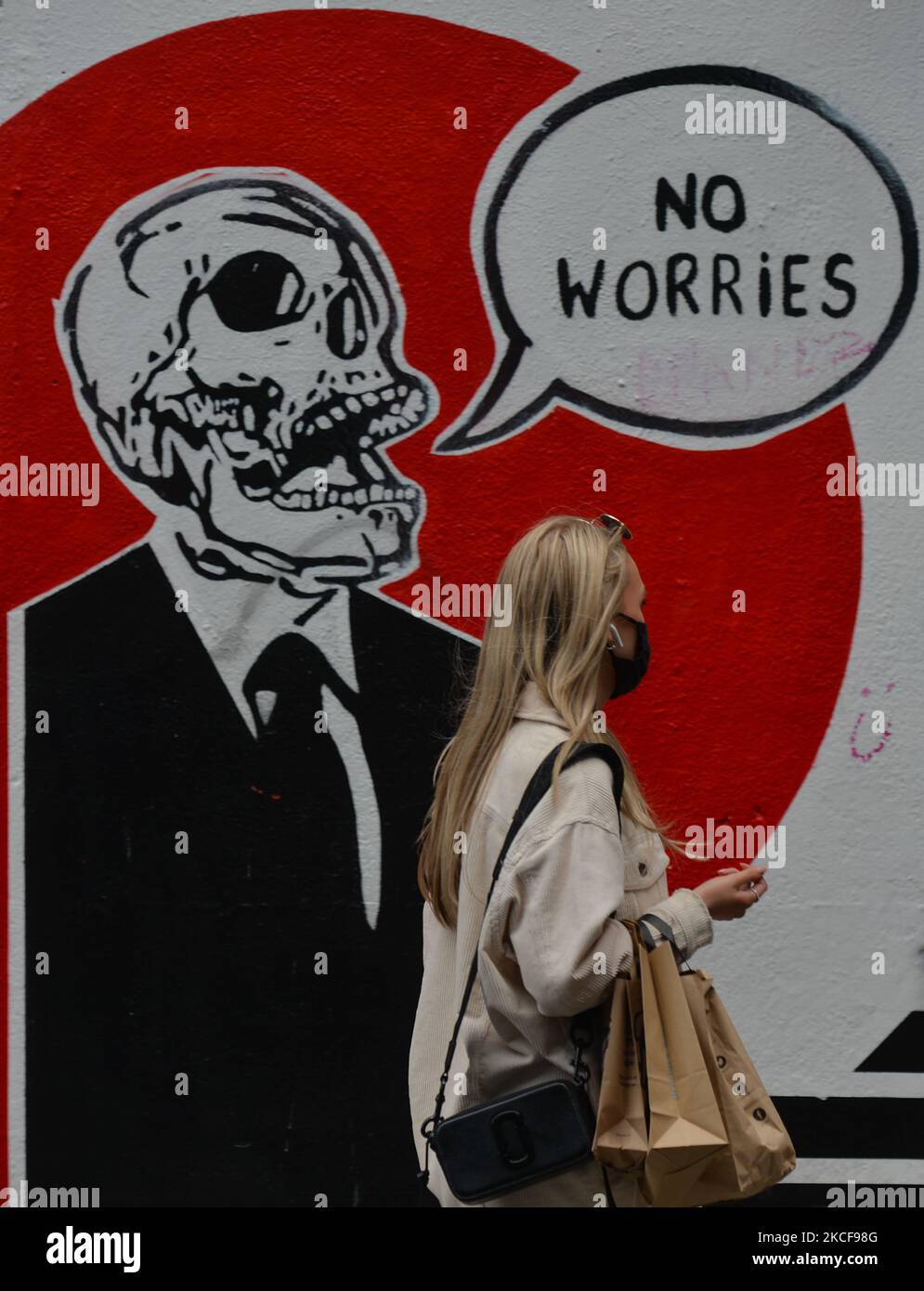 A woman walks past a mural with the words 'NO WORRIES' in the center of Dublin. On Wednesday, 26 May 2021, in Dublin, Ireland. (Photo by Artur Widak/NurPhoto) Stock Photo