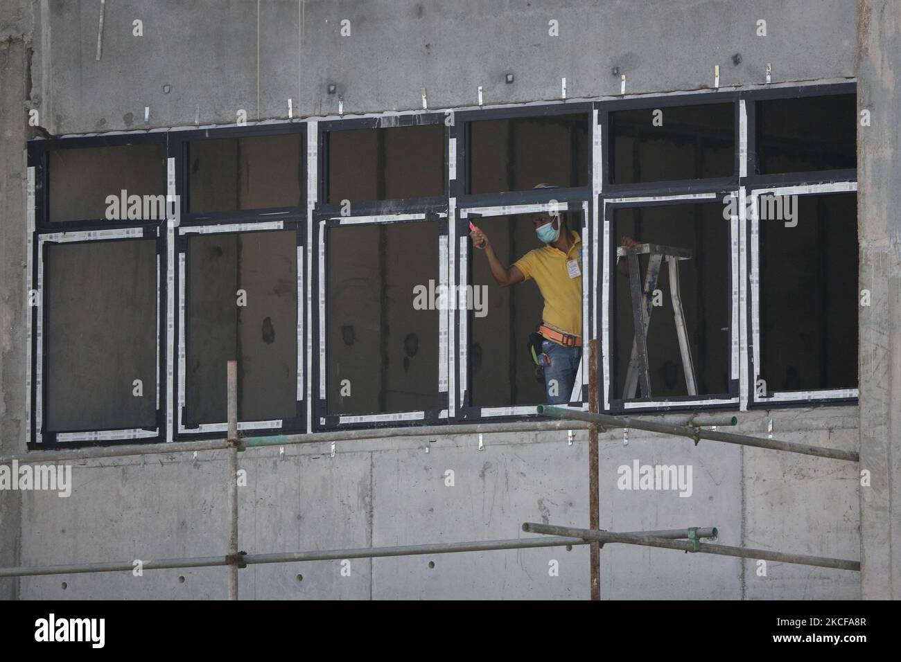 A migrant worker works at a building construction site on May 28, 2021 in Singapore. Singapore enters a month long heightened alert from May 16 to June 13 to curb the spread of COVID-19 cases in the local community. New restrictions on movements and activities have been introduced such as limiting social interaction to two, prohibiting dining out and a reduced operating capacity at shopping malls, offices and attractions. On May 17, the construction industry stakeholders appealed to Multi-Ministry Taskforce to bring in foreign workers in a safe and controlled manner after the built environment Stock Photo