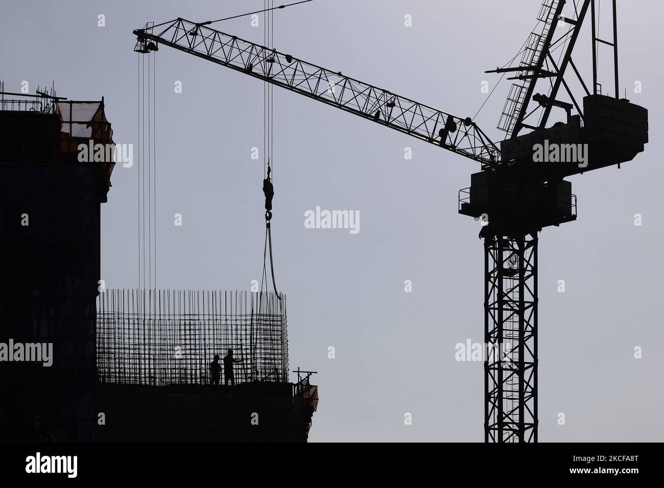 Migrant workers work at a building construction site on May 28, 2021 in Singapore. Singapore enters a month long heightened alert from May 16 to June 13 to curb the spread of COVID-19 cases in the local community. New restrictions on movements and activities have been introduced such as limiting social interaction to two, prohibiting dining out and a reduced operating capacity at shopping malls, offices and attractions. On May 17, the construction industry stakeholders appealed to Multi-Ministry Taskforce to bring in foreign workers in a safe and controlled manner after the built environment i Stock Photo