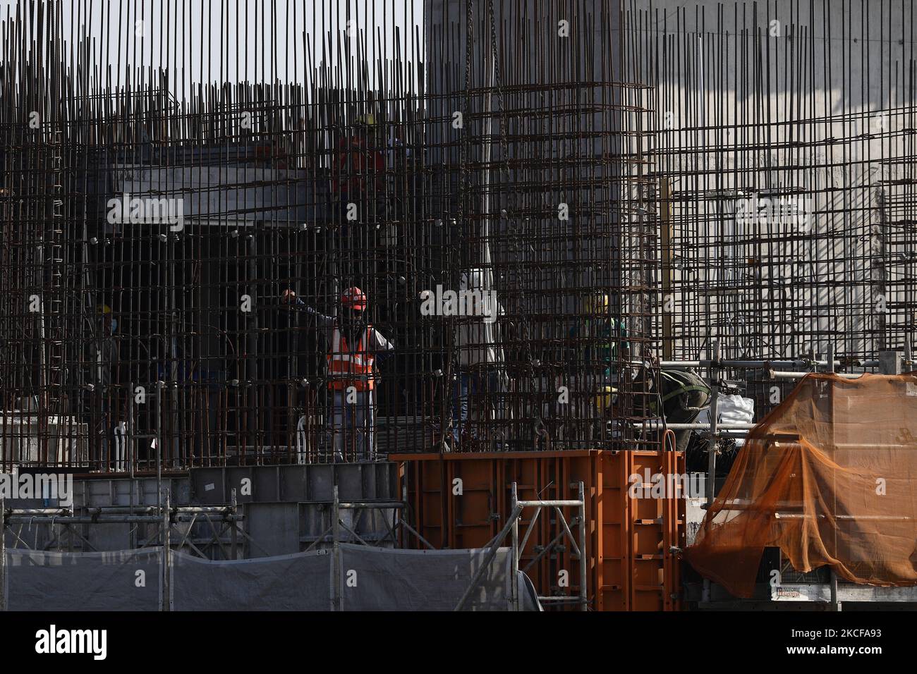 Migrant workers work at a building construction site on May 28, 2021 in Singapore. Singapore enters a month long heightened alert from May 16 to June 13 to curb the spread of COVID-19 cases in the local community. New restrictions on movements and activities have been introduced such as limiting social interaction to two, prohibiting dining out and a reduced operating capacity at shopping malls, offices and attractions. On May 17, the construction industry stakeholders appealed to Multi-Ministry Taskforce to bring in foreign workers in a safe and controlled manner after the built environment i Stock Photo