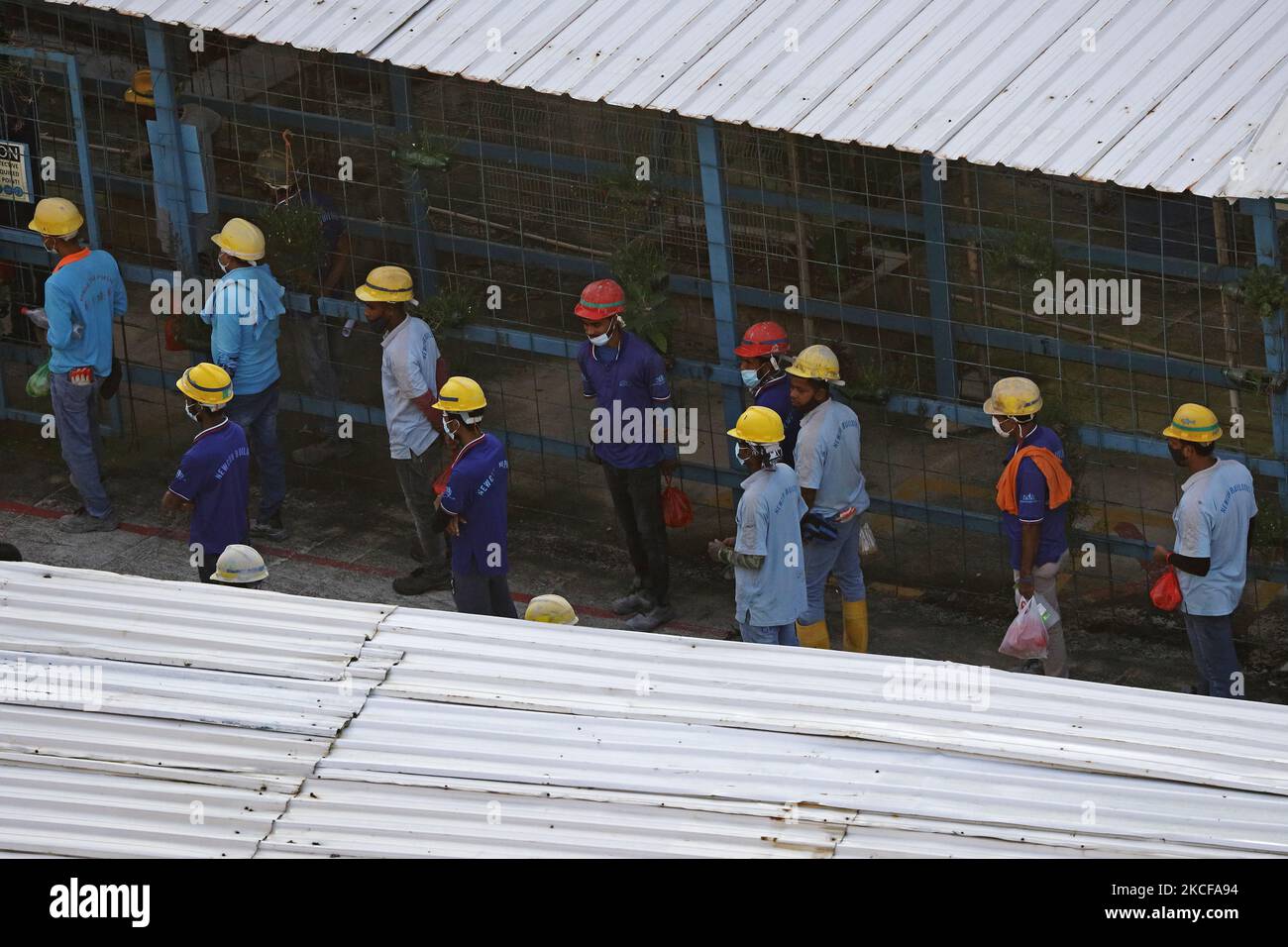 Migrant workers queue to enter a building construction site on May 28, 2021 in Singapore. Singapore enters a month long heightened alert from May 16 to June 13 to curb the spread of COVID-19 cases in the local community. New restrictions on movements and activities have been introduced such as limiting social interaction to two, prohibiting dining out and a reduced operating capacity at shopping malls, offices and attractions. On May 17, the construction industry stakeholders appealed to Multi-Ministry Taskforce to bring in foreign workers in a safe and controlled manner after the built enviro Stock Photo