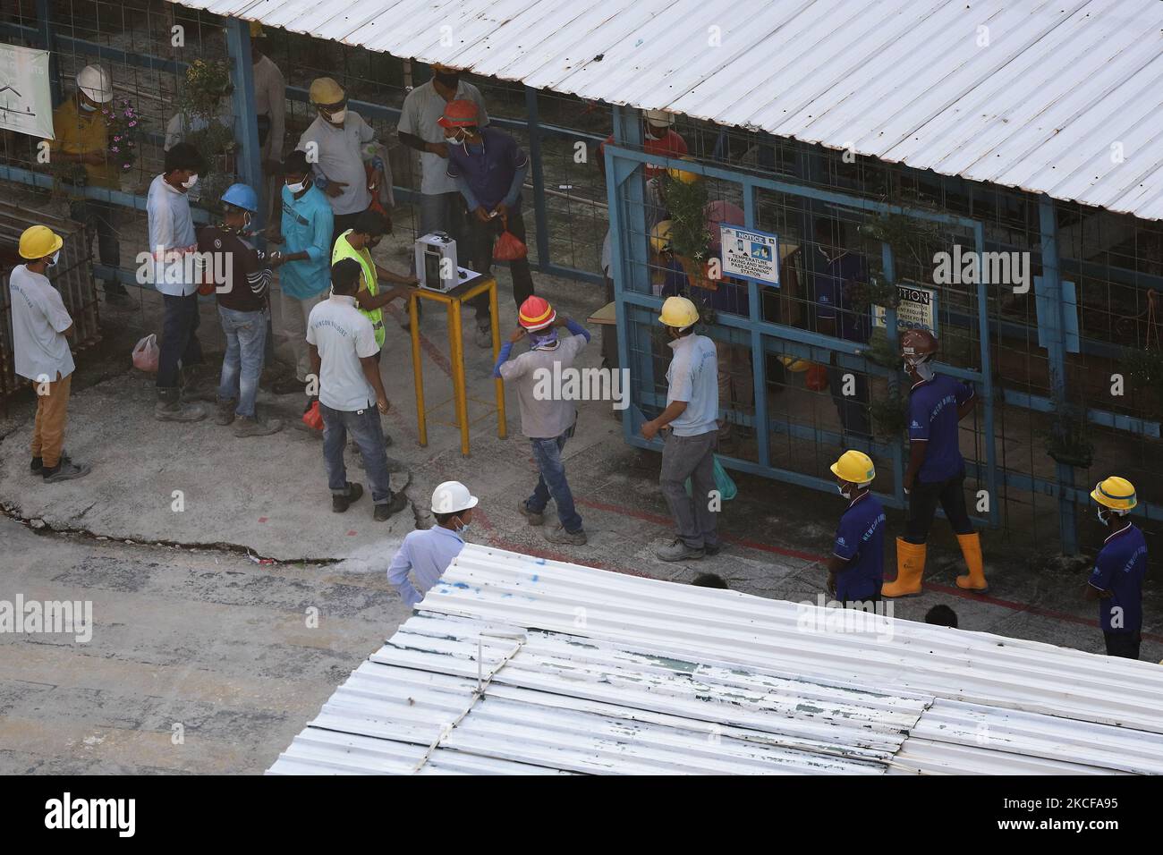Migrant workers queue to enter a building construction site on May 28, 2021 in Singapore. Singapore enters a month long heightened alert from May 16 to June 13 to curb the spread of COVID-19 cases in the local community. New restrictions on movements and activities have been introduced such as limiting social interaction to two, prohibiting dining out and a reduced operating capacity at shopping malls, offices and attractions. On May 17, the construction industry stakeholders appealed to Multi-Ministry Taskforce to bring in foreign workers in a safe and controlled manner after the built enviro Stock Photo